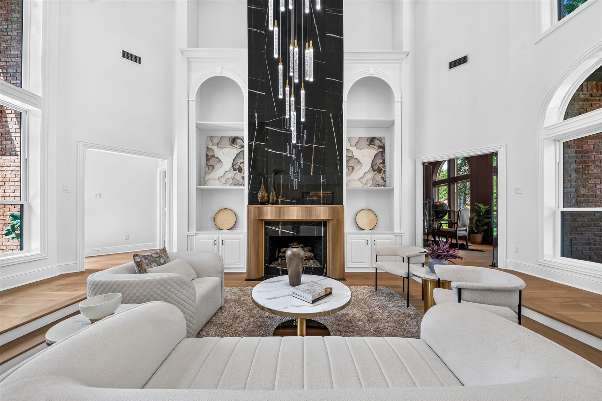 46 Pebble Cove Drive, The Woodlands, TX 77381 Stunning living room with soaring ceilings, a dramatic black marble fireplace, and elegant built-in shelving, offering a perfect blend of luxury and comfort.
