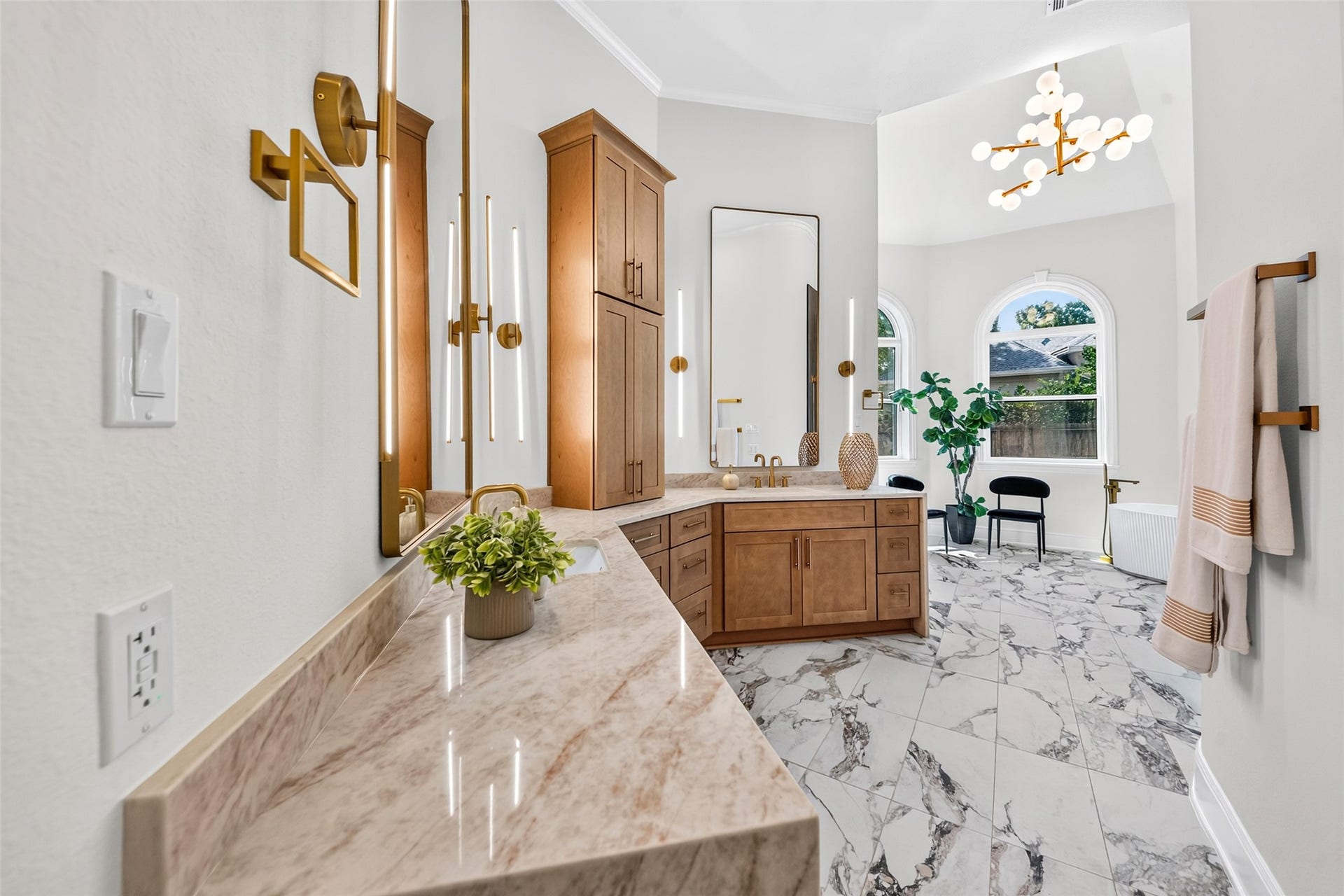 46 Pebble Cove Drive, The Woodlands, TX 77381 Luxurious bathroom featuring elegant marble countertops, modern lighting, and ample natural light from large arched windows.