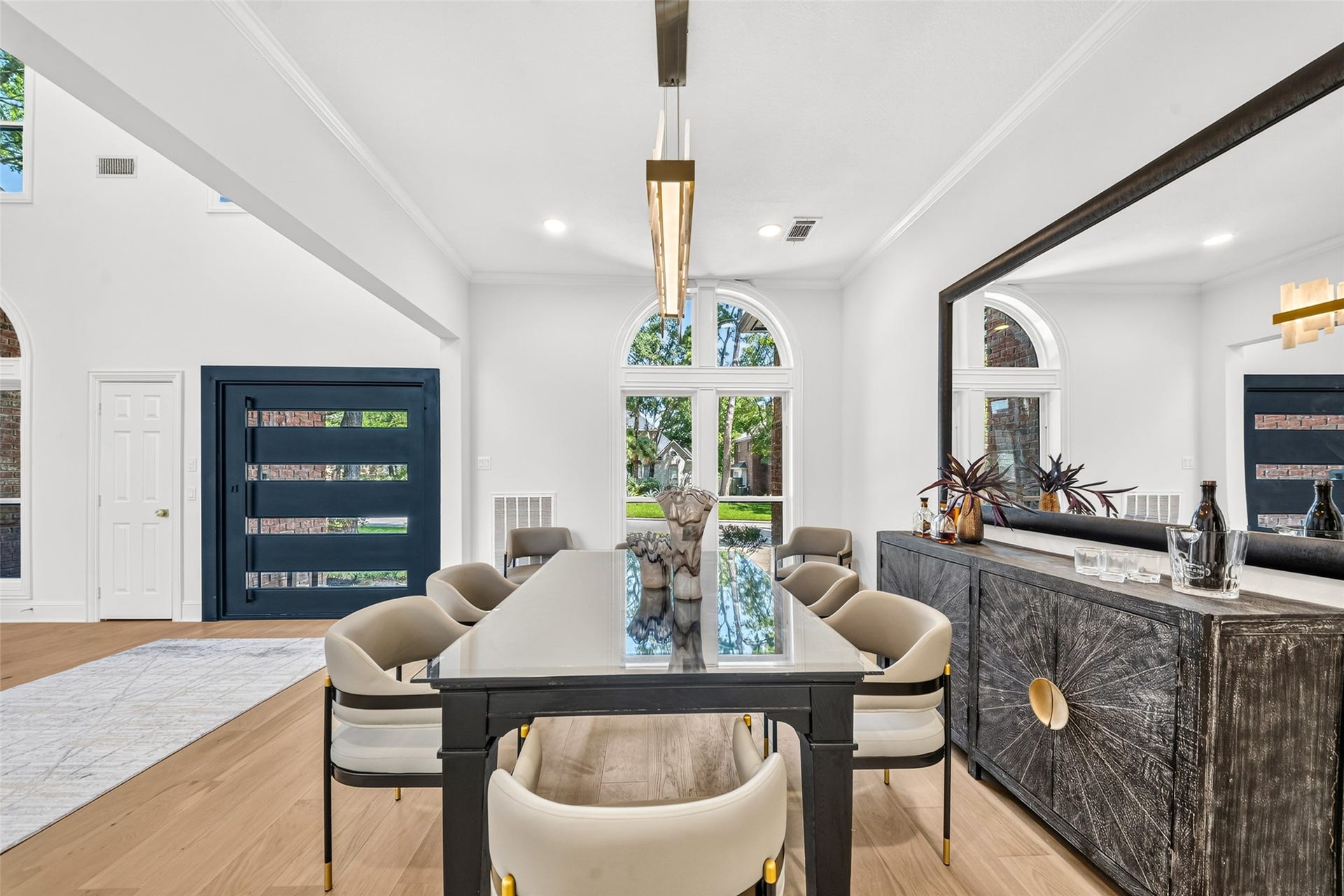 46 Pebble Cove Drive, The Woodlands, TX 77381 Elegant dining room with a modern table and plush chairs, complemented by large arched windows that flood the space with natural light. A sleek sideboard and stylish lighting add sophistication.