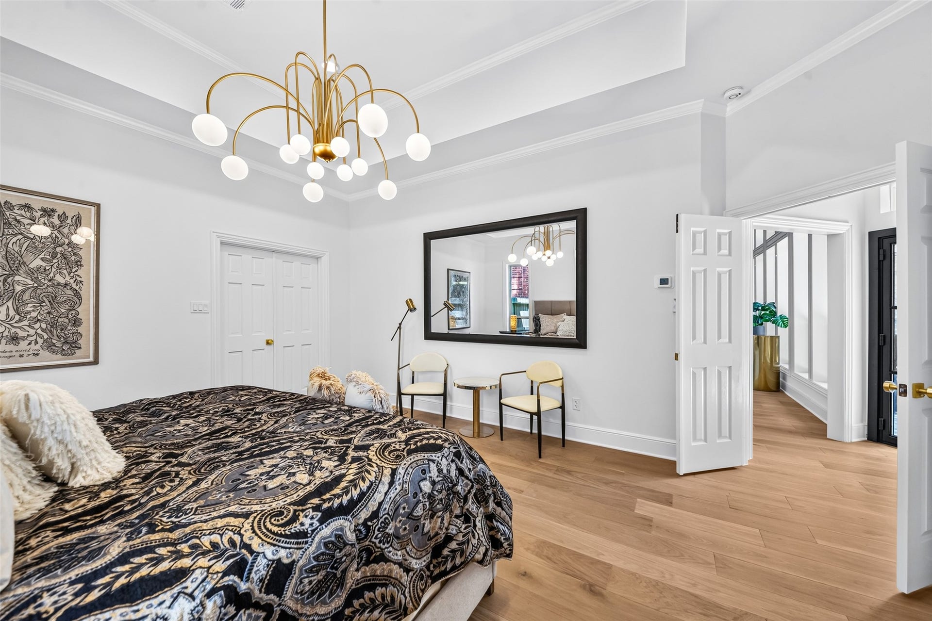 46 Pebble Cove Drive, The Woodlands, TX 77381 Elegant bedroom featuring a striking chandelier, cozy seating area, and stylish decor, with rich wood flooring and ample natural light.