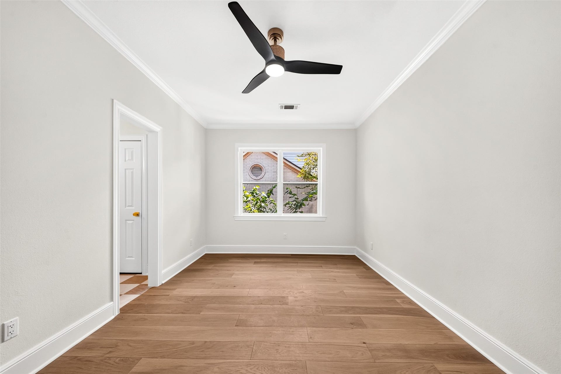 46 Pebble Cove Drive, The Woodlands, TX 77381 Bright and spacious room featuring hardwood flooring, a modern ceiling fan, and a large window inviting natural light.