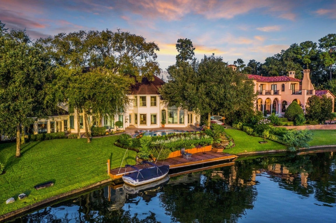 35 W Isle Place, The Woodlands, TX 77381 Rear exterior showcasing the elegant home, expansive lawn, and serene waterfront setting.