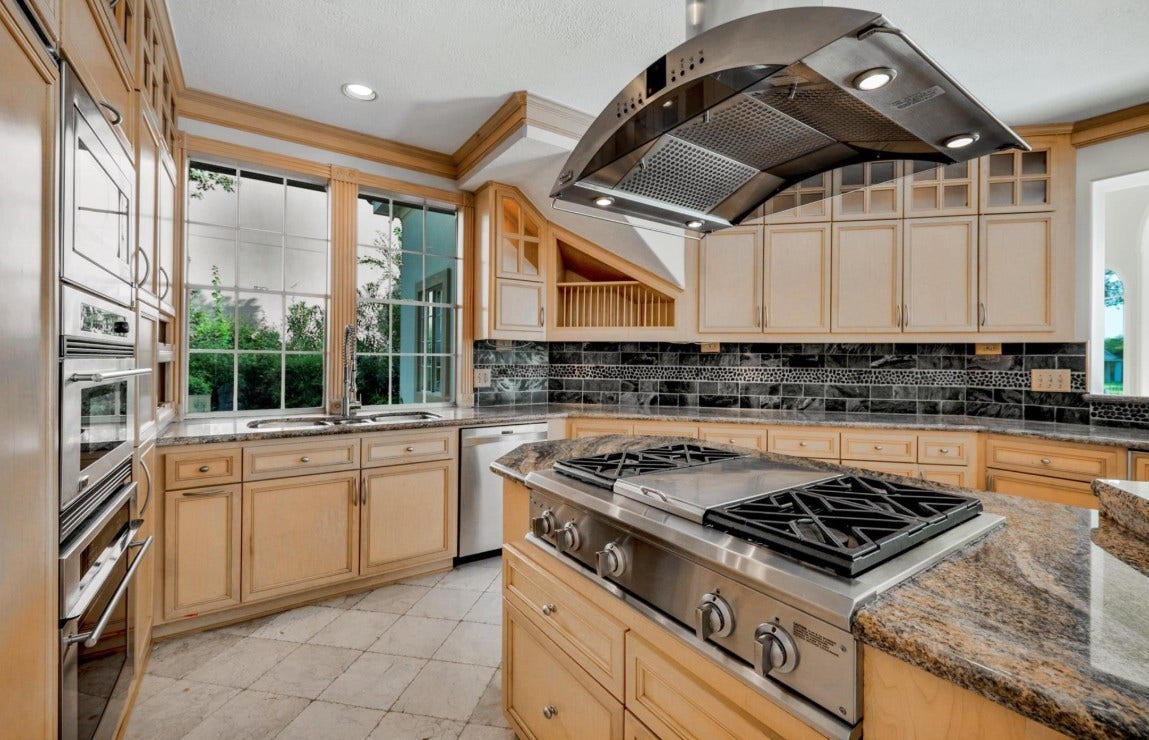 35 W Isle Place, The Woodlands, TX 77381 Oversized center island with gas cooktop, custom vent hood, and ample prep space for entertaining.