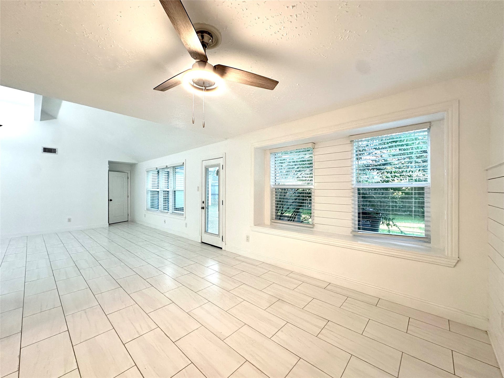 3411 Cannon Ridge Drive, Richmond, TX 77406 Bright and airy living space with large windows, sleek tile flooring, and a modern ceiling fan, offering a seamless flow to the outdoors.