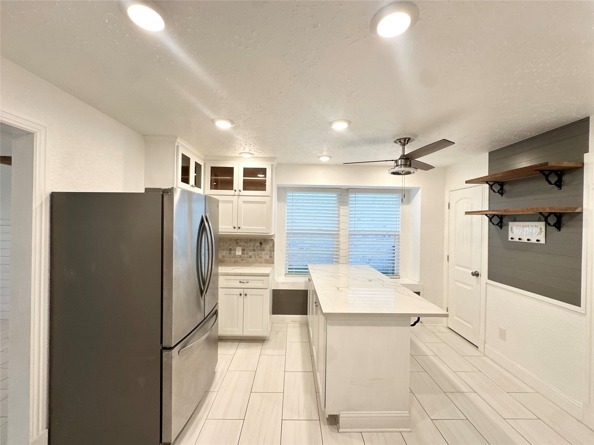 3411 Cannon Ridge Drive, Richmond, TX 77406 Bright and airy room featuring a modern ceiling fan, light blue walls with white wainscoting, and rich dark wood flooring, complemented by large windows for ample natural light.