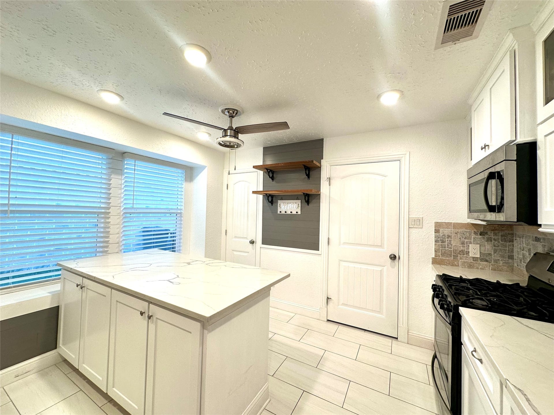 3411 Cannon Ridge Drive, Richmond, TX 77406 Bright and spacious room featuring elegant dark wood flooring, soft blue walls, and a ceiling fan, complemented by large windows that invite natural light.