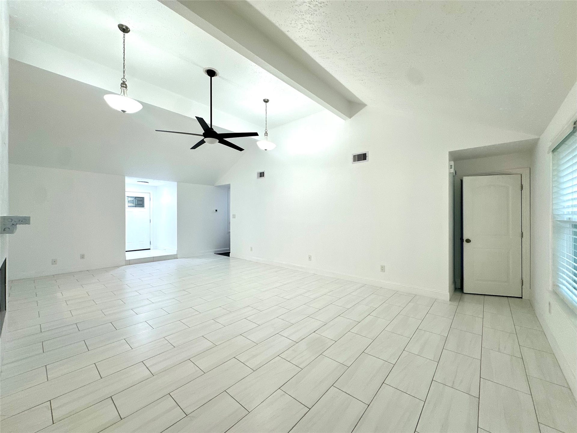3411 Cannon Ridge Drive, Richmond, TX 77406 Spacious living area with light blue walls and sleek tile flooring, featuring modern ceiling fans and ample natural light from large windows, creating an airy and inviting atmosphere.