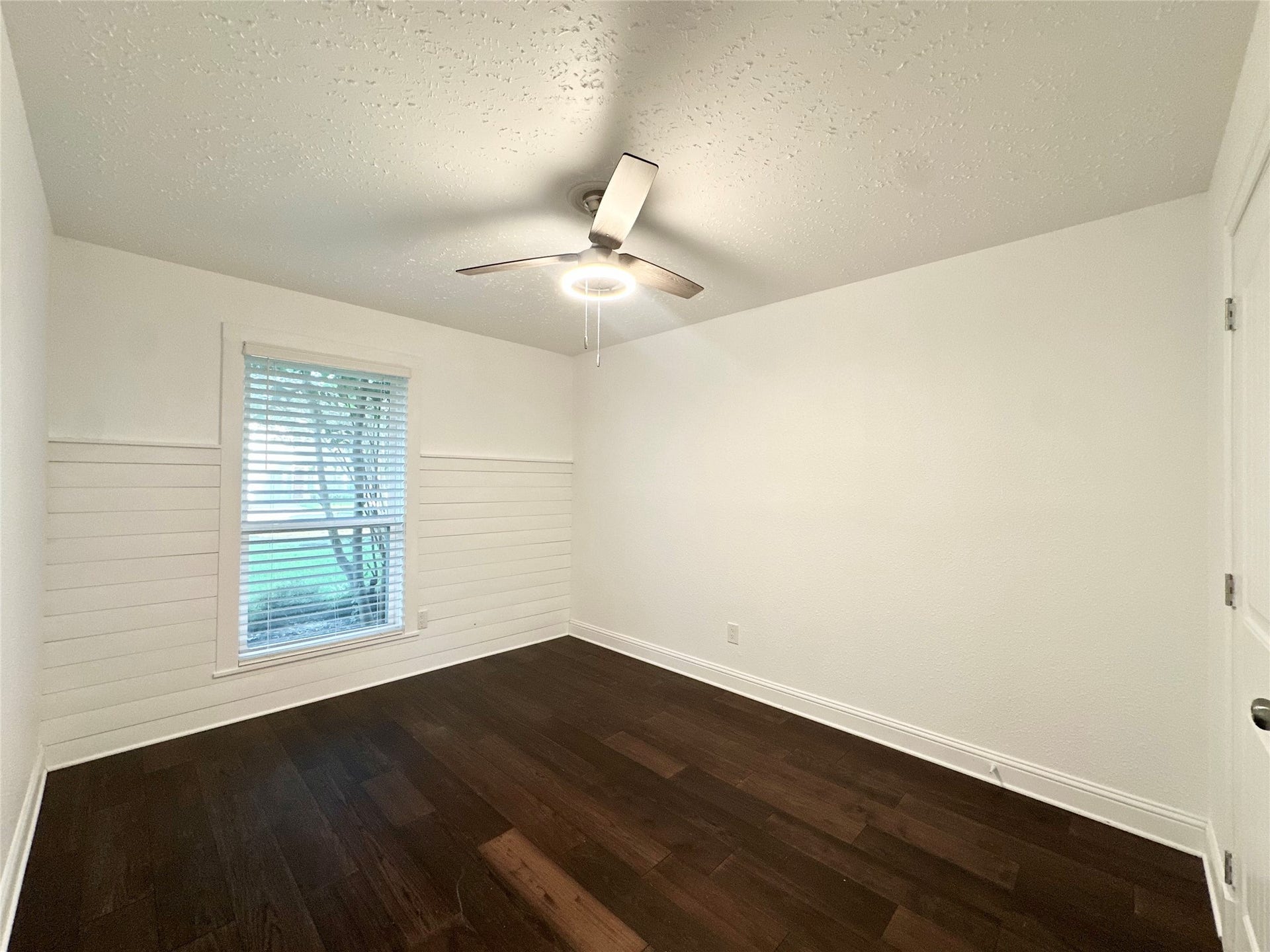 3411 Cannon Ridge Drive, Richmond, TX 77406 Spacious room featuring elegant hardwood flooring and modern ceiling fan, complemented by soft, neutral walls and two classic white panel doors.
