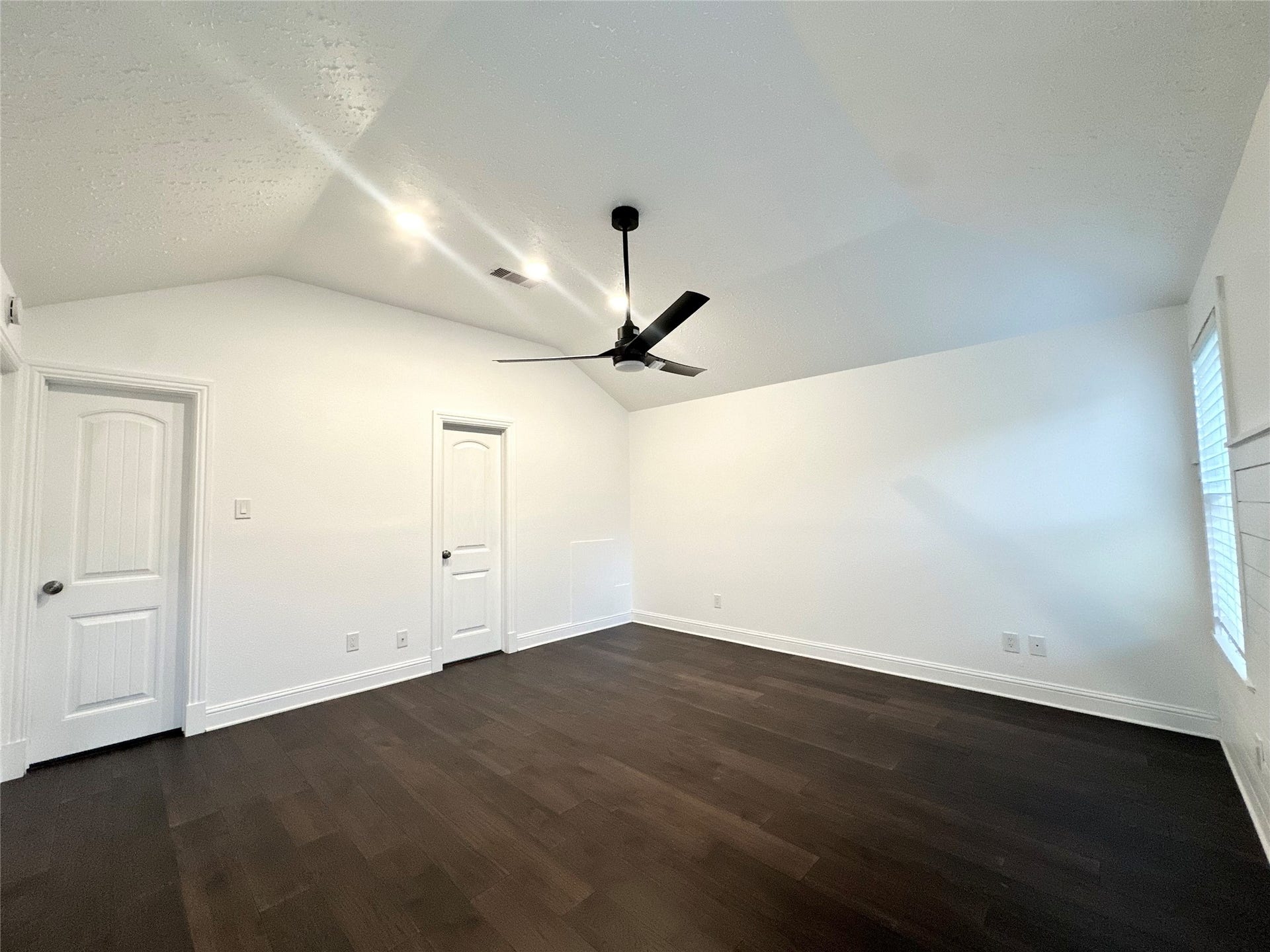 3411 Cannon Ridge Drive, Richmond, TX 77406 Bright and inviting room featuring rich wood flooring, a modern ceiling fan, and a large window with elegant white trim and paneling, offering ample natural light.