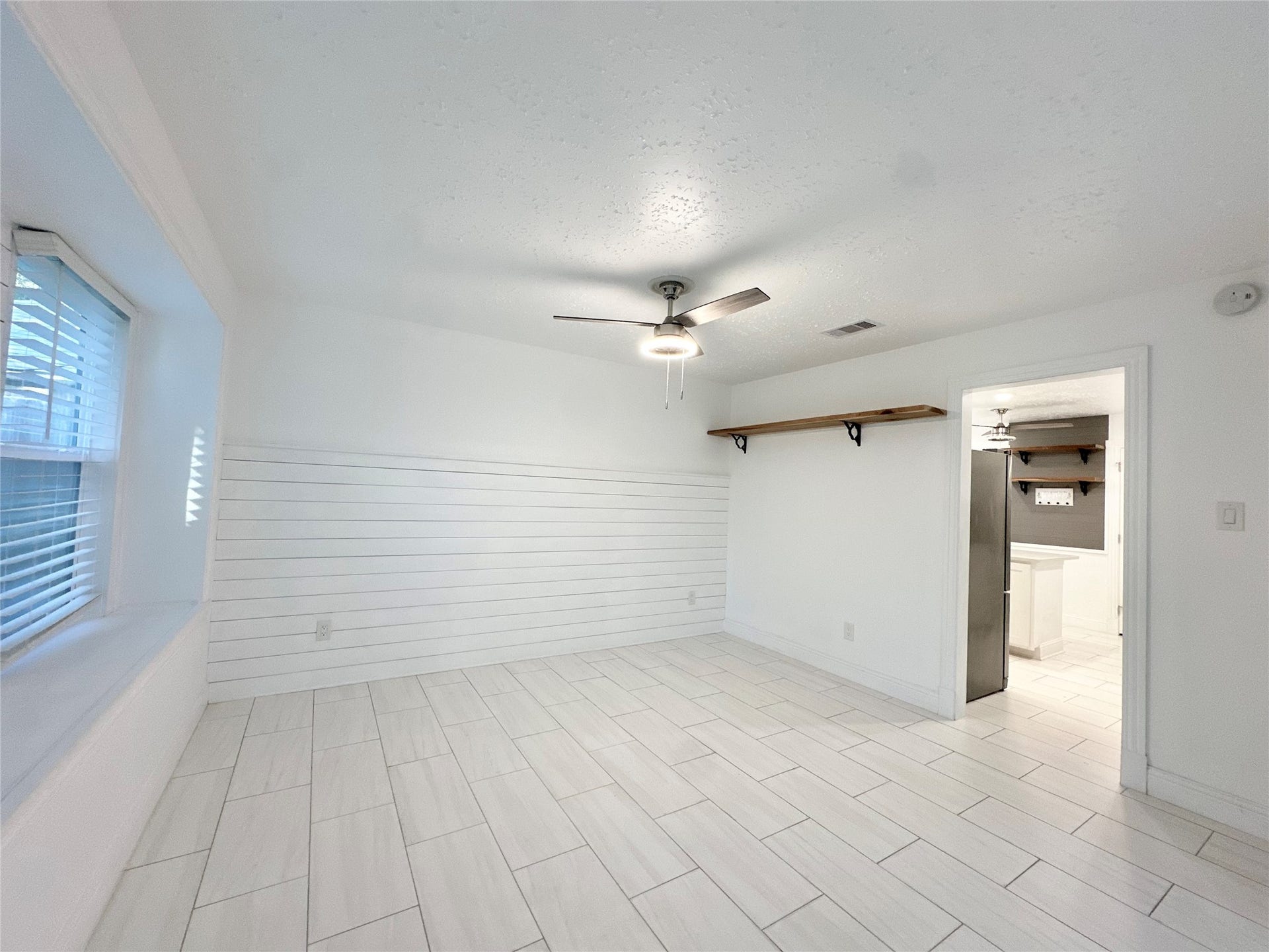 3411 Cannon Ridge Drive, Richmond, TX 77406 Stylish kitchen with modern stainless steel appliances, elegant white cabinetry, and a chic marble-patterned island, complemented by a sleek ceiling fan and ambient lighting.