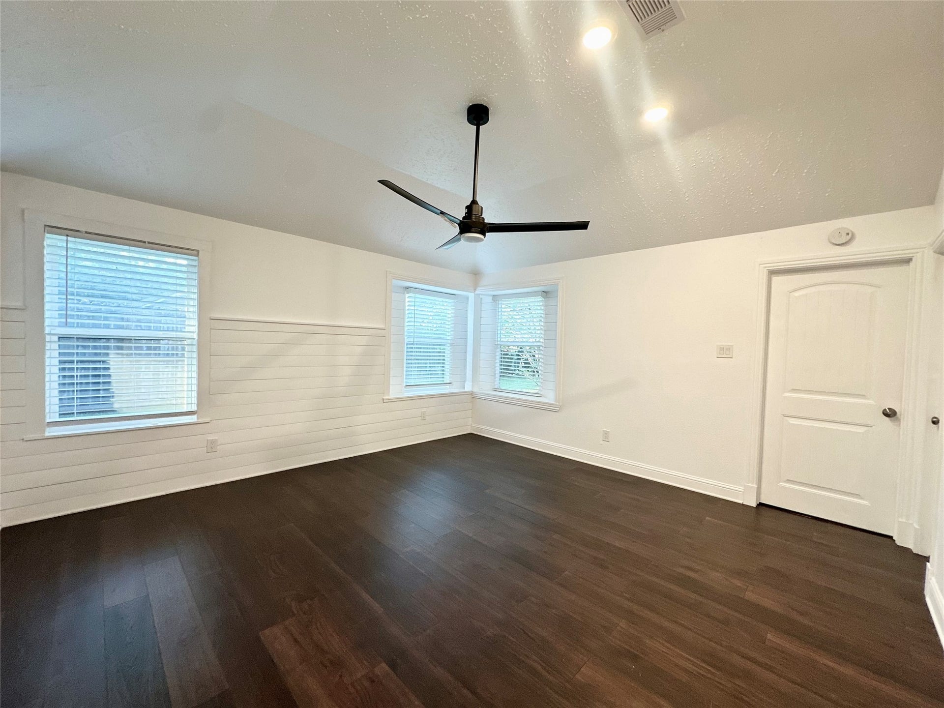 3411 Cannon Ridge Drive, Richmond, TX 77406 Spacious room with vaulted ceilings, elegant dark wood flooring, and a ceiling fan, complemented by soft blue walls and a large window for natural light.