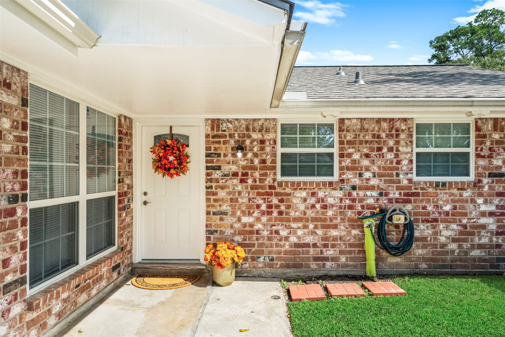 3402 Dovie Drive, Spring, TX 77380 Covered entryway features classic brickwork, large windows, a clean concrete walkway, and a neatly maintained lawn. The outside white wood areas of the home have been freshly painted, giving the exterior a crisp, refreshed appearance.