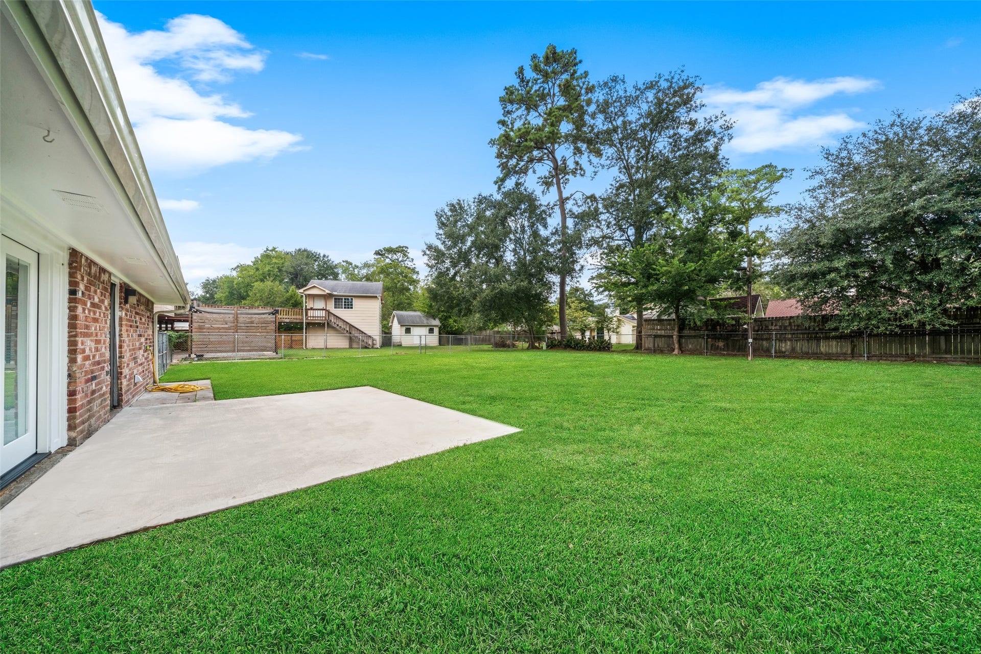 3402 Dovie Drive, Spring, TX 77380 This expansive backyard offers plenty of open green space, mature shade trees, and a large concrete patio perfect for outdoor seating, grilling, or entertaining. The spacious lawn provides ample room for children, pets, gardening, or future outdoor additions, creating a versatile and inviting area for relaxing and enjoying the outdoors.