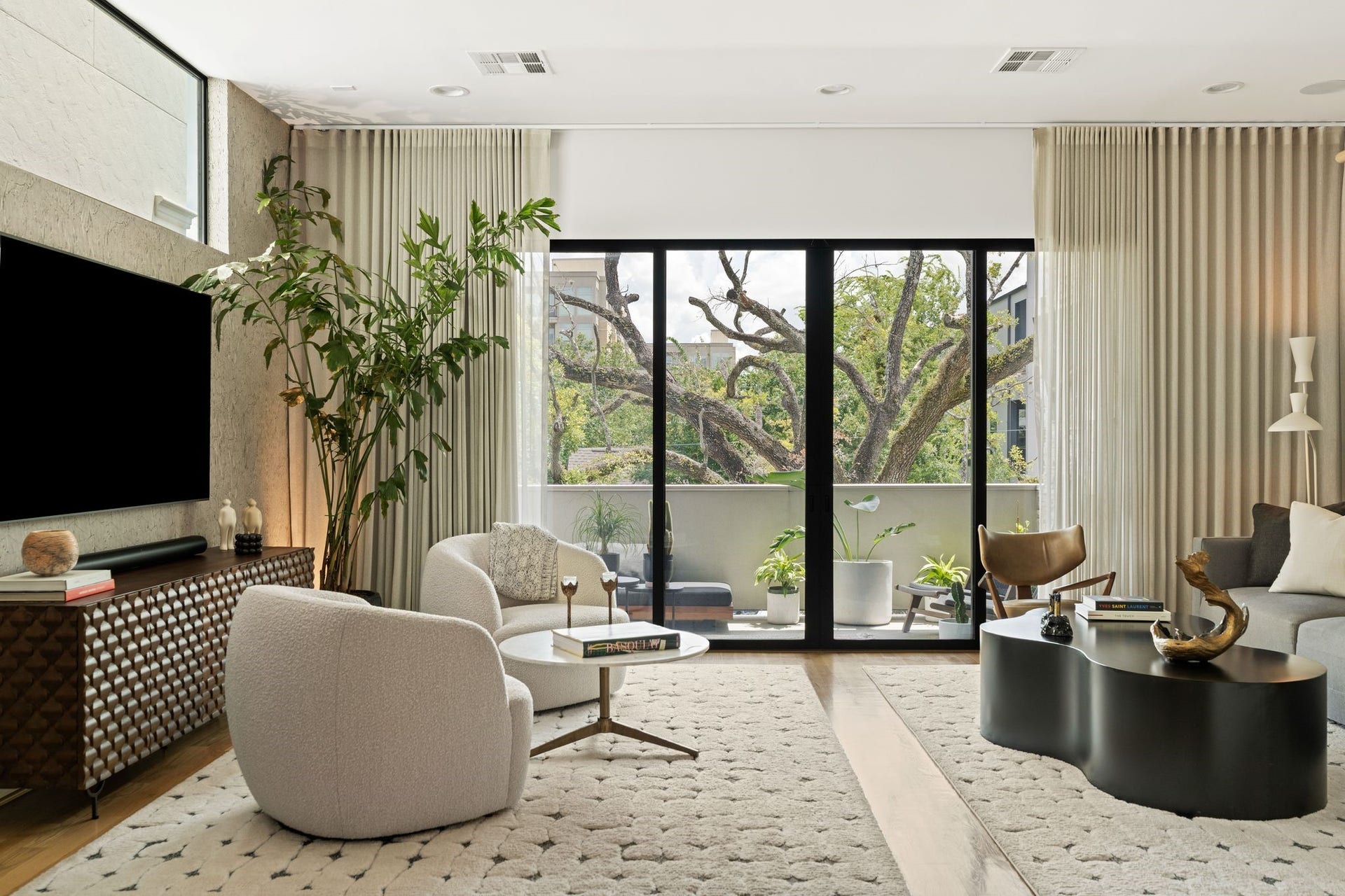 2622 Greenbriar Drive, Houston, TX 77098 Light-filled second-floor living room with hardwood floors, professionally curated interiors, custom drapery and expansive sliding glass doors opening to the covered terrace and mature oak canopy.