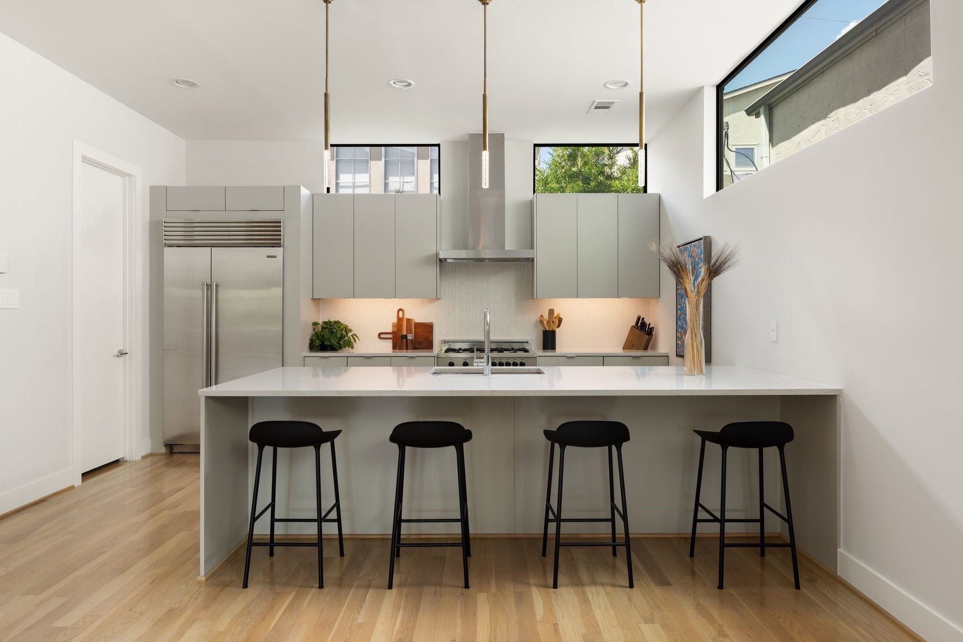2622 Greenbriar Drive, Houston, TX 77098 Designer kitchen overlooking the dining area with counter seating, statement pendant lighting, under-cabinet lighting, hardwood floors, and high-end stainless steel appliances.