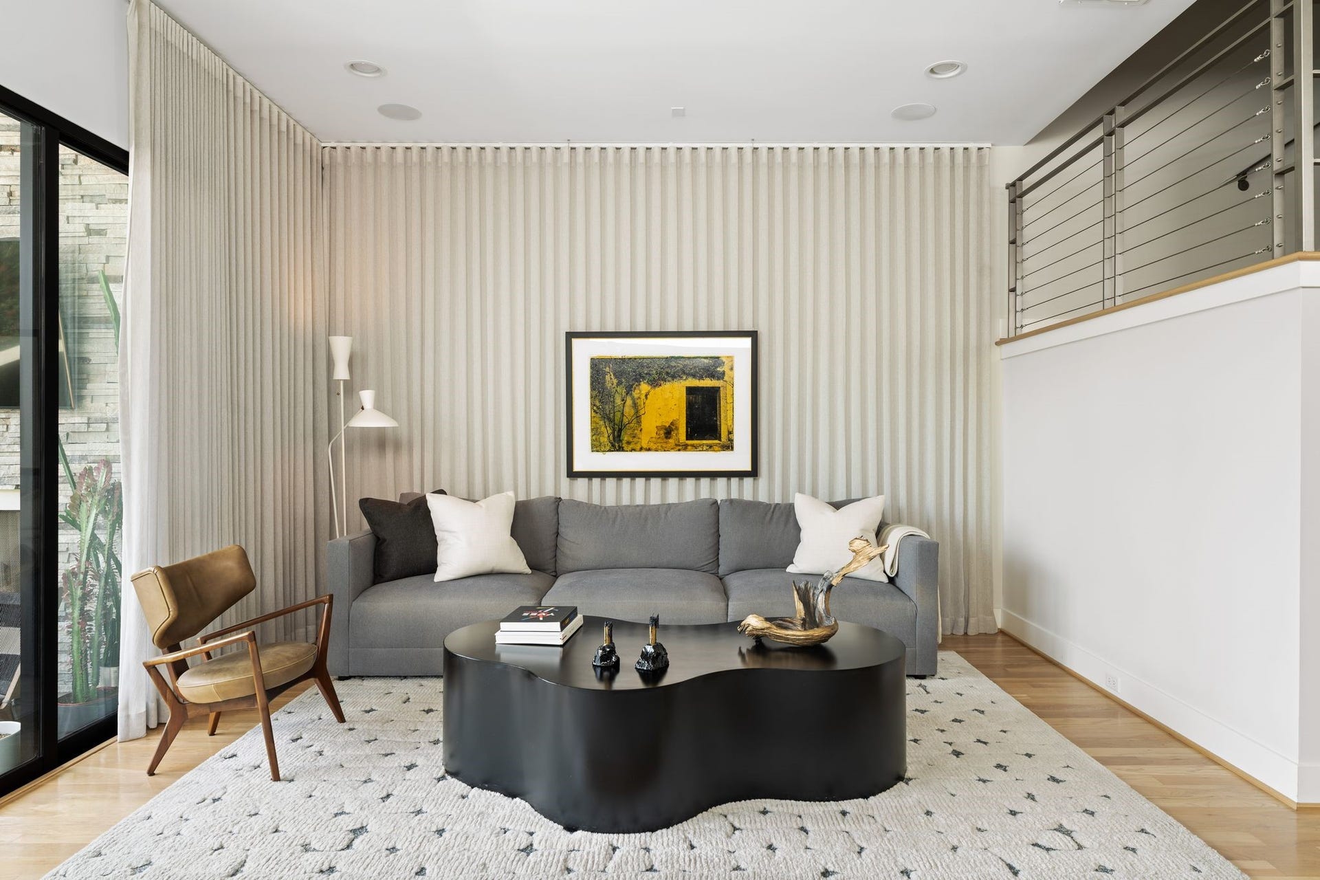 2622 Greenbriar Drive, Houston, TX 77098 Professionally curated living room features dramatic custom drapery extending across the wall, ceiling-suspended artwork, hardwood floors, and a sophisticated layered aesthetic.