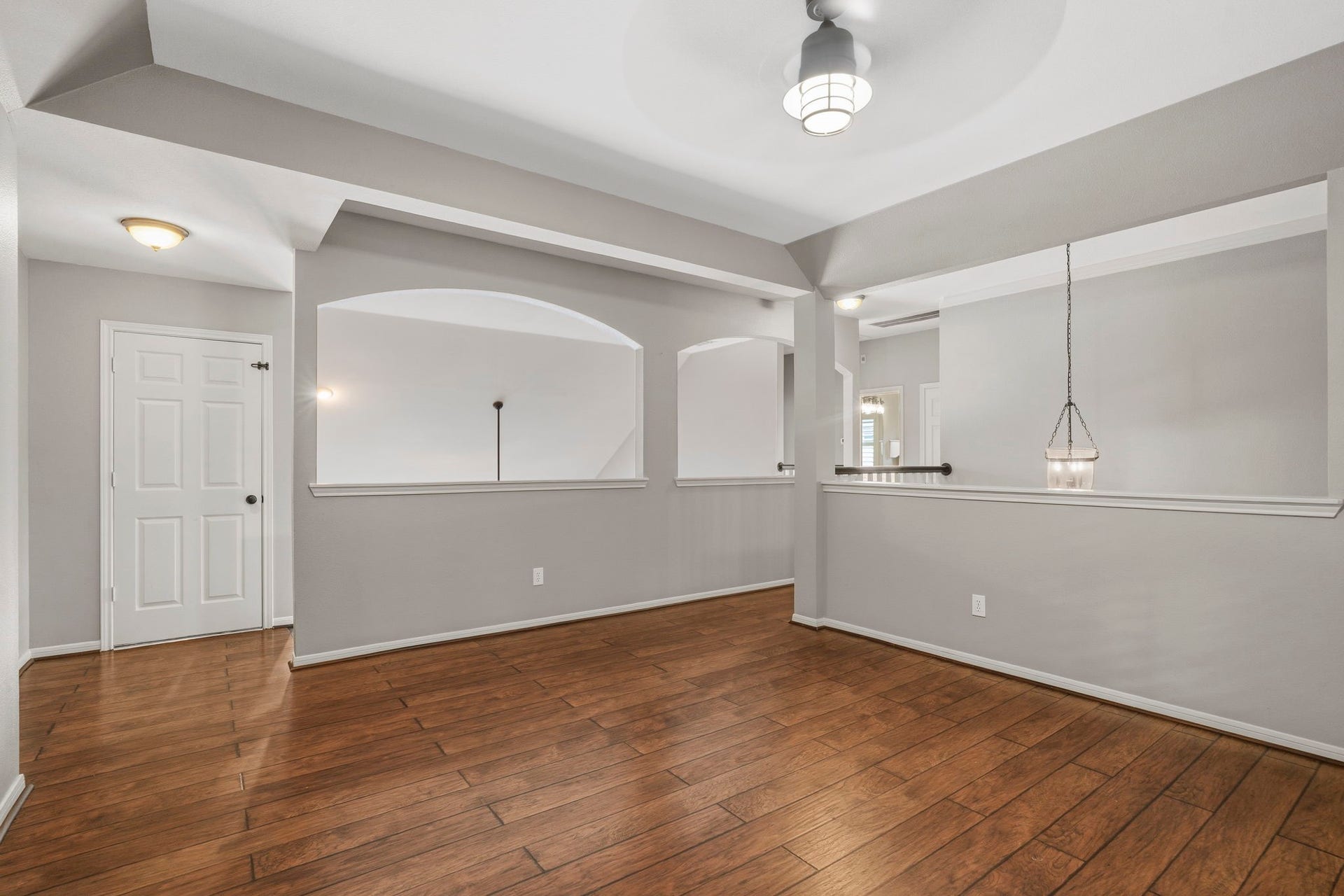 9730 Harrison Lane, Missouri City, TX 77459 Open game room loft showcasing architectural wall cutouts, tray ceiling detail, wood-look LVP floors, and clear sightlines across the second floor.