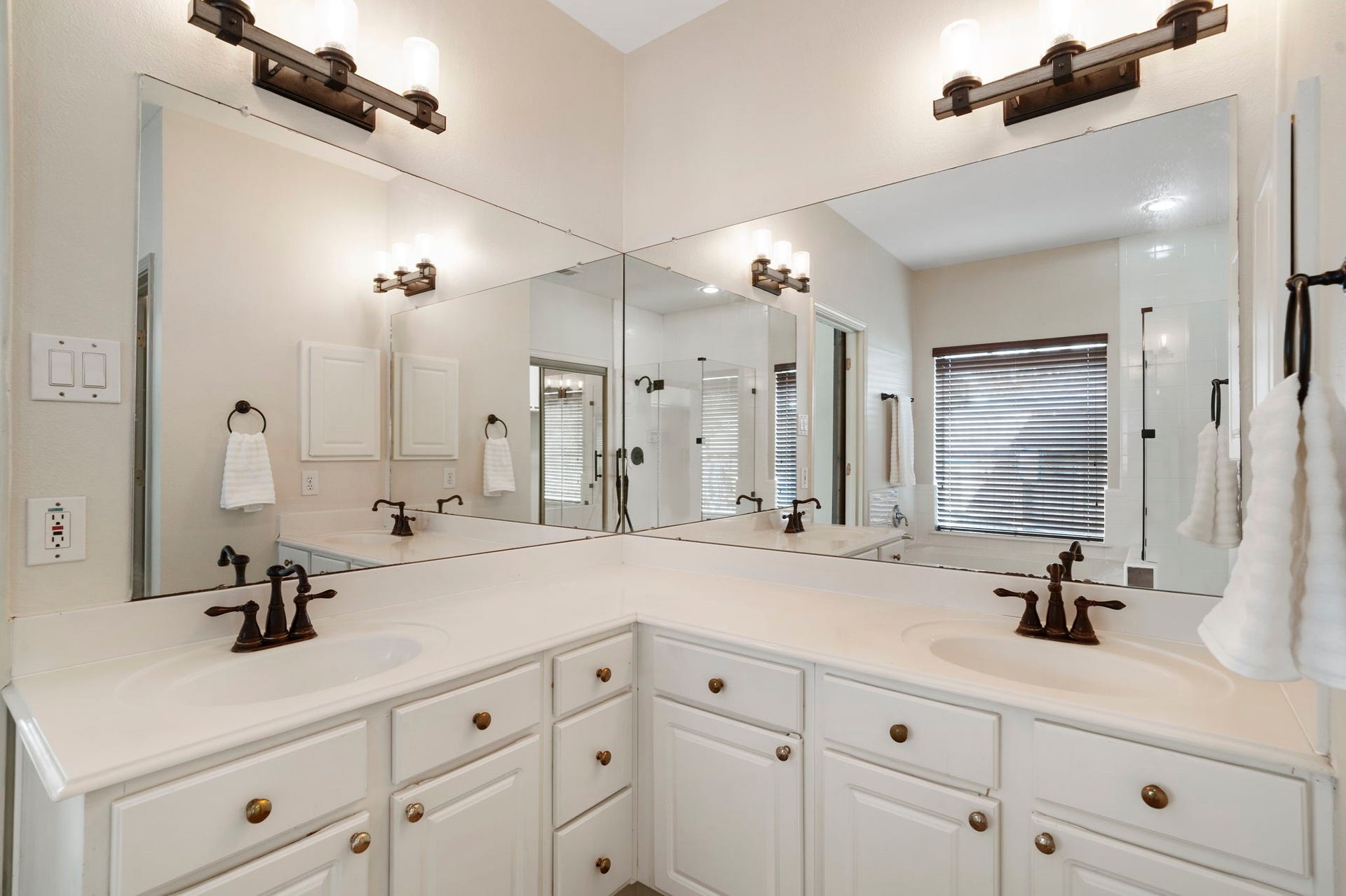 9730 Harrison Lane, Missouri City, TX 77459 Primary en-suite bathroom highlighting the wide corner L-shaped vanity with crisp white cabinetry, dual sinks, oil-rubbed bronze fixtures, and full-height vanity mirrors.