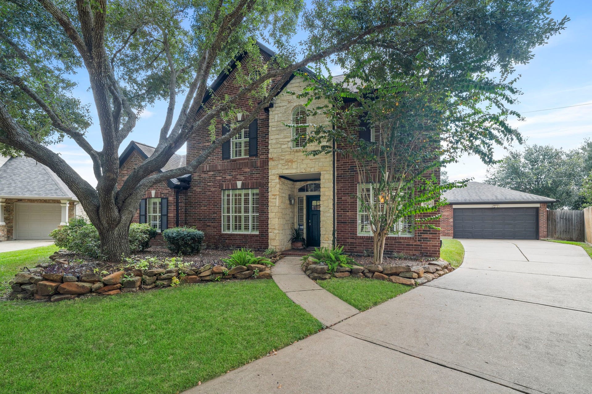 9730 Harrison Lane, Missouri City, TX 77459 Expansive front curb appeal showing the long concrete driveway leading to the detached garage, flanked by lush green lawn and mature landscaping.