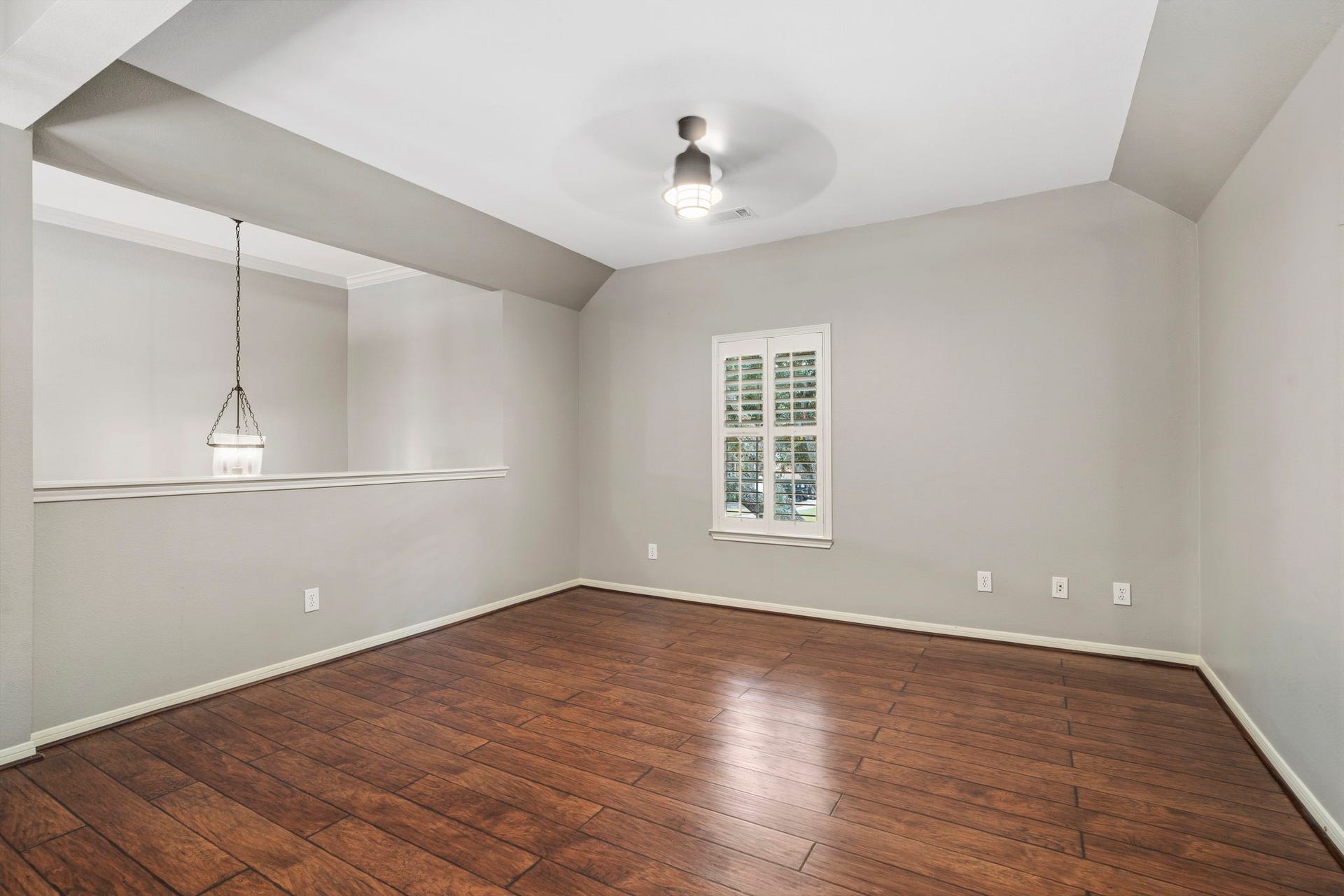 9730 Harrison Lane, Missouri City, TX 77459 Expansive upper-level game room loft featuring wood-look LVP flooring, custom window shutters, modern overhead fan lighting, and a half-wall overlooking the stairwell.