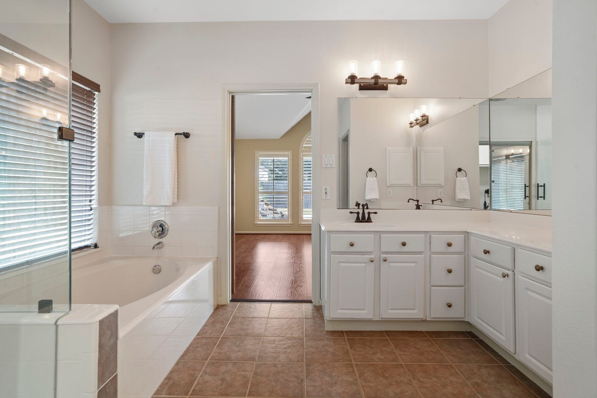 9730 Harrison Lane, Missouri City, TX 77459 Comprehensive primary bath overview illustrating the ceramic tile flooring, deep soaking tub, glass shower stall, extended double vanity, and seamless open doorway into the main bedroom suite.