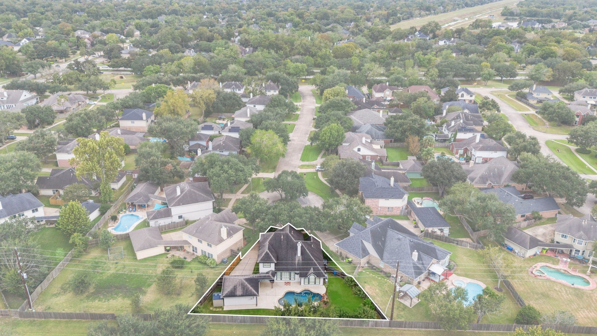 9730 Harrison Lane, Missouri City, TX 77459 High-altitude neighborhood aerial highlighting the home's substantial roofline, private pool area, and mature suburban surroundings within the Sienna community.