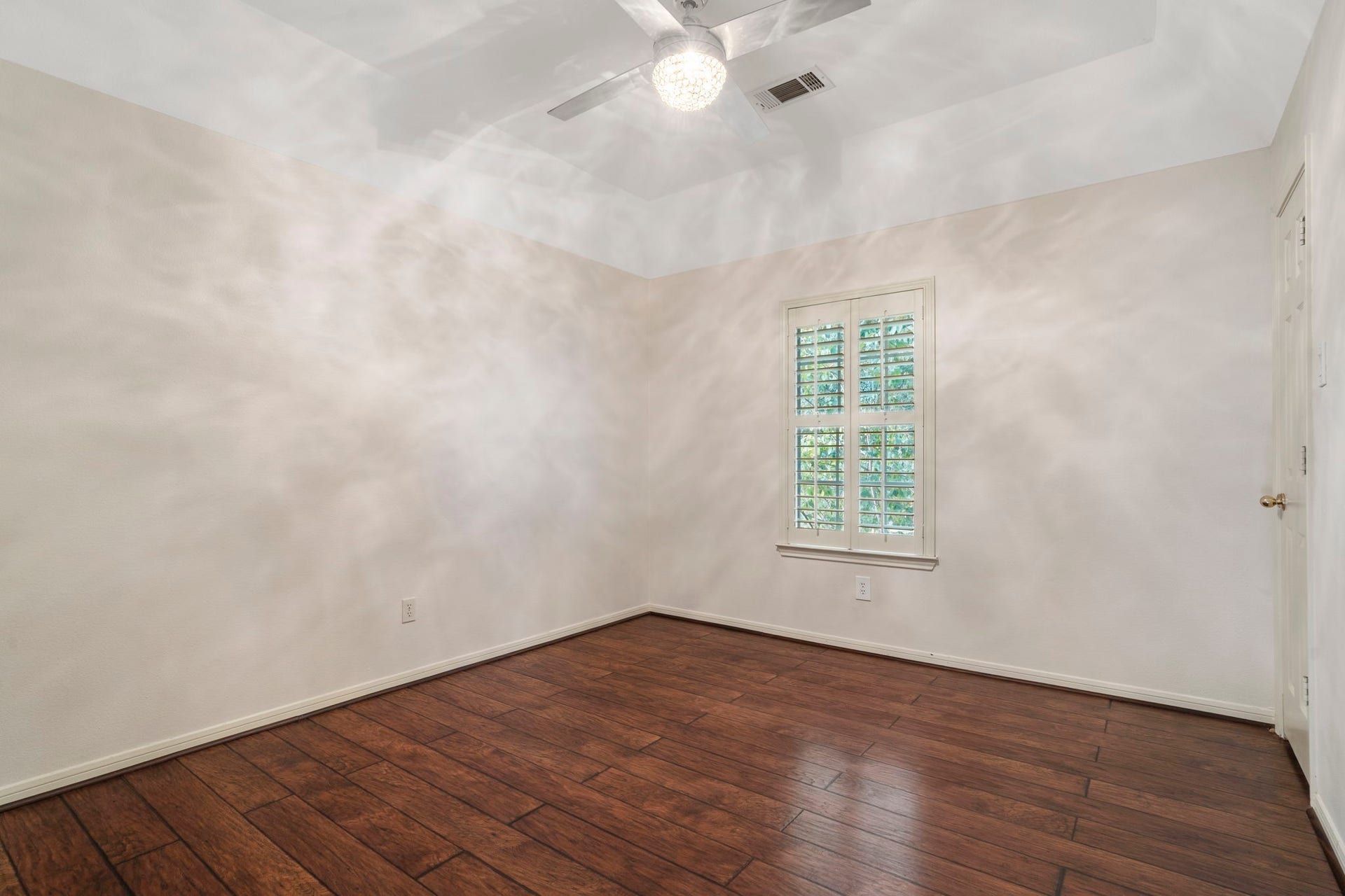9730 Harrison Lane, Missouri City, TX 77459 Bright secondary bedroom showcasing high vaulted ceilings, modern overhead lighting, wood-look LVP flooring, and a custom shuttered window.