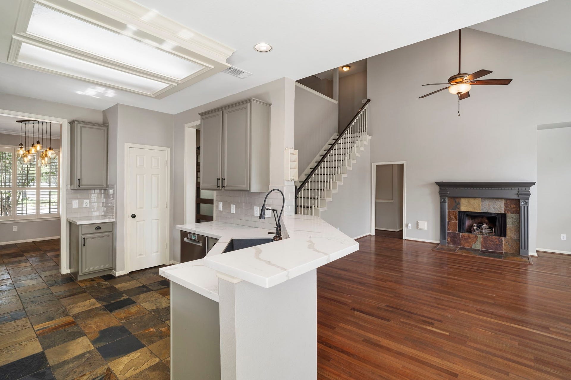9730 Harrison Lane, Missouri City, TX 77459 Seamless open-concept view from behind the kitchen counter looking directly into the primary living room, corner gas fireplace, open staircase, and high vaulted ceiling line.