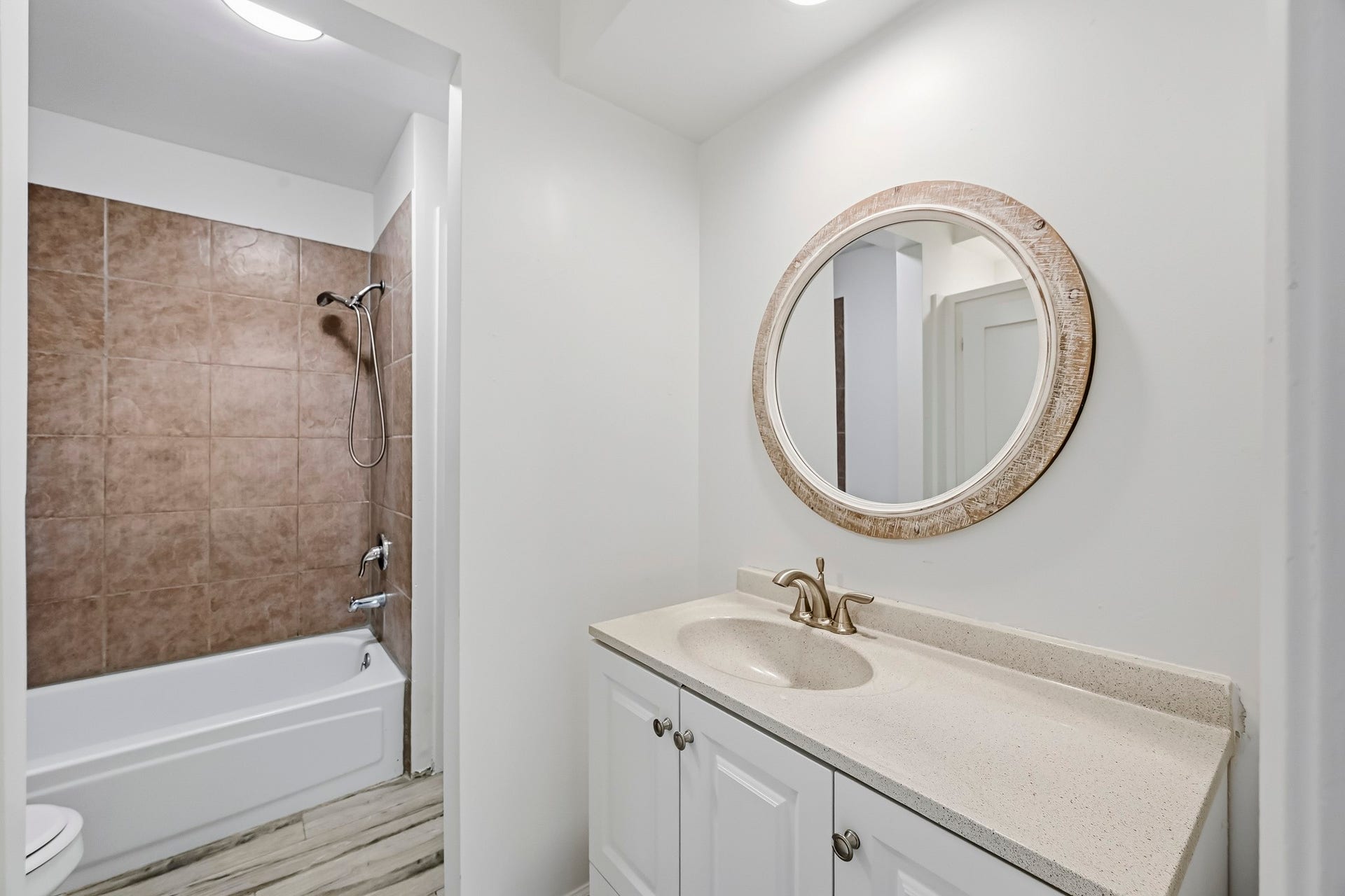 22711 Provincial Boulevard, Katy, TX 77450 This secondary bathroom combines everyday comfort with a clean, functional layout. The grooming area features an expansive vanity counter with an integrated basin and under-counter storage, highlighted by a decorative circular mirror and overhead lighting