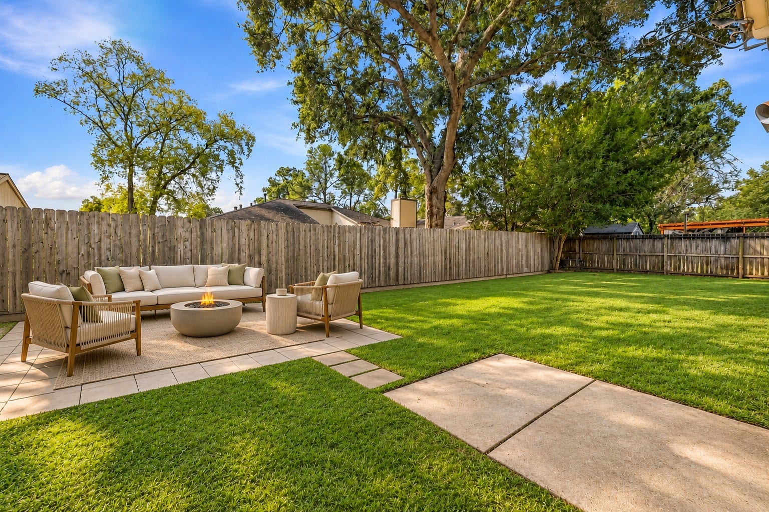 22711 Provincial Boulevard, Katy, TX 77450 Virtually Staged: A paved patio zone provides a dedicated open-air lounge around a glowing central fire bowl, linked by stepping stones to adjacent hardscape pads.