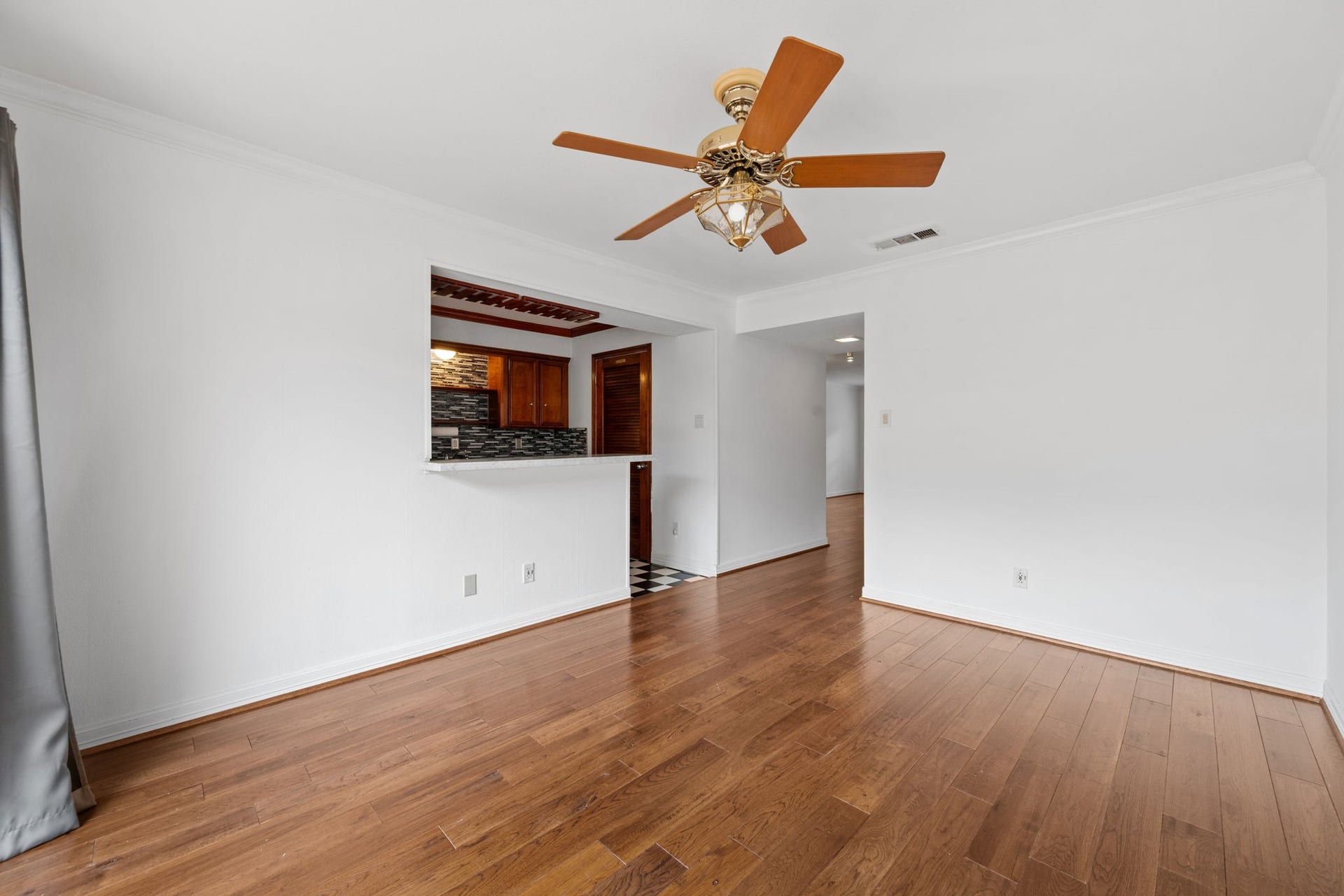 5819 Valley Forge Drive, #91, Houston, TX 77057 Bright and inviting living space with elegant hardwood floors, a stylish ceiling fan, and a pass-through window to the kitchen, enhancing openness and connectivity.