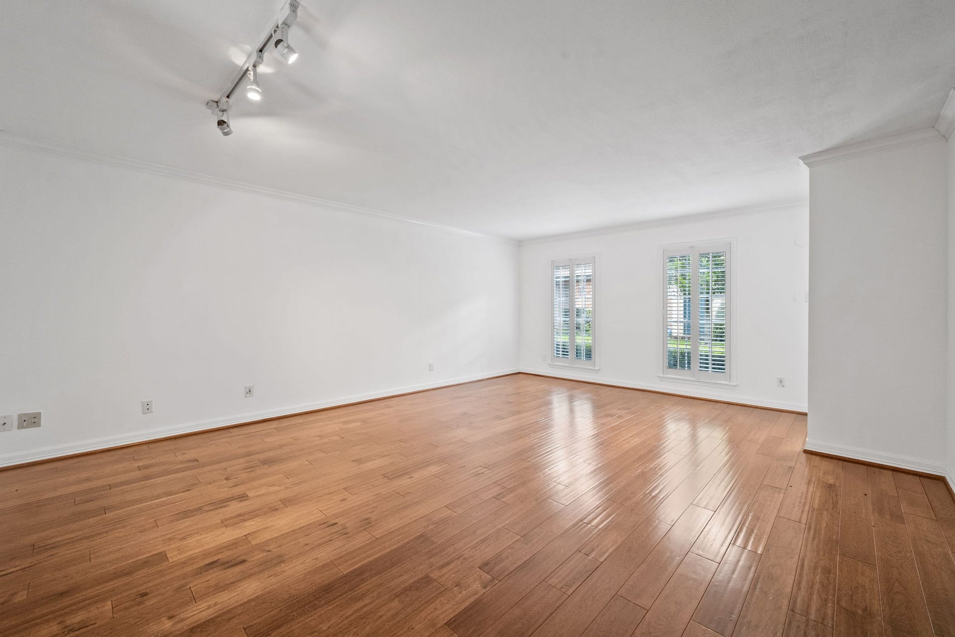 5819 Valley Forge Drive, #91, Houston, TX 77057 Spacious, light-filled living area with sleek hardwood floors and large windows adorned with elegant shutters, perfect for modern living.