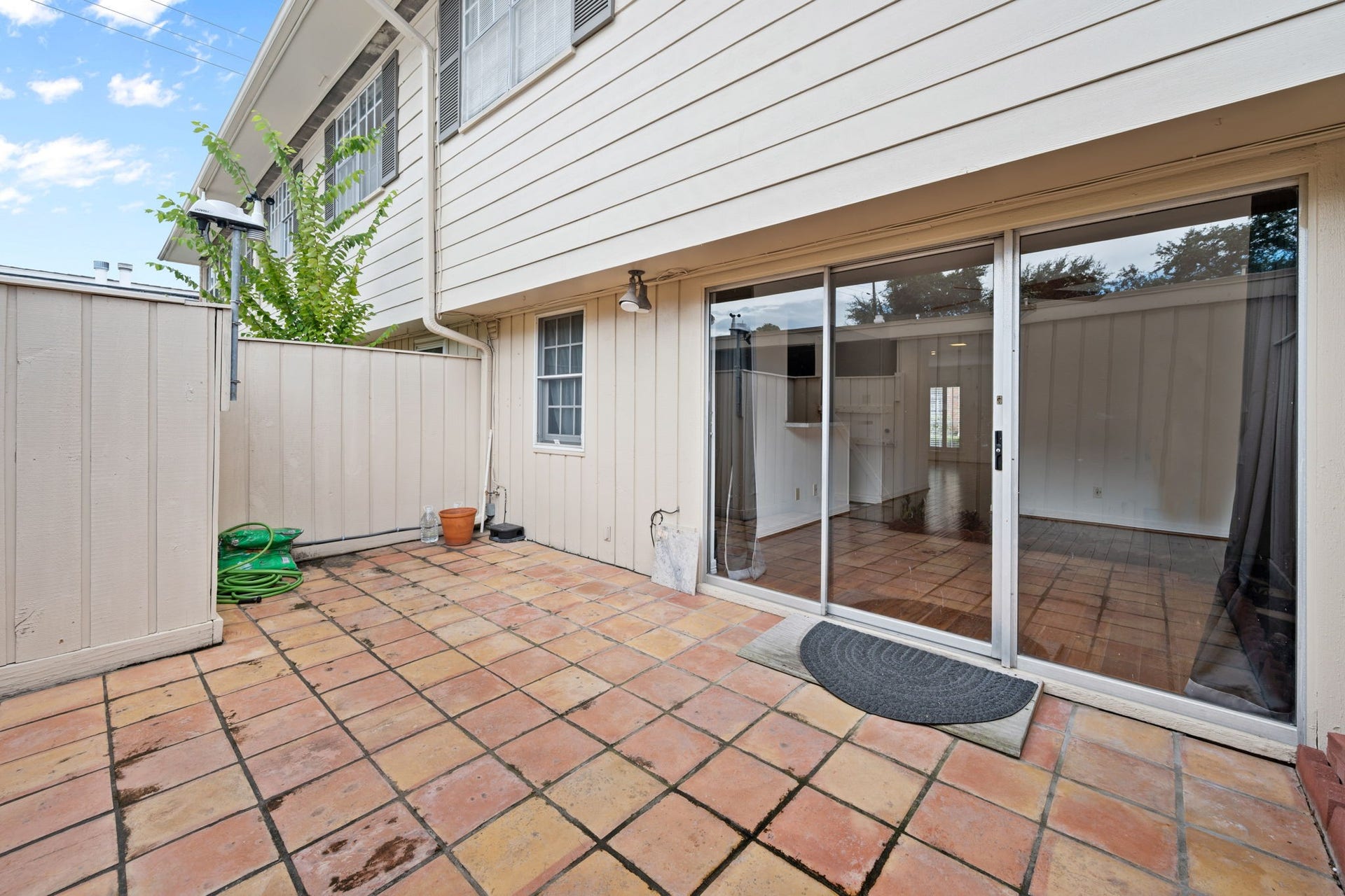 5819 Valley Forge Drive, #91, Houston, TX 77057 Charming private patio with terracotta tile flooring, perfect for outdoor relaxation, featuring sliding glass doors that open to a cozy interior space.