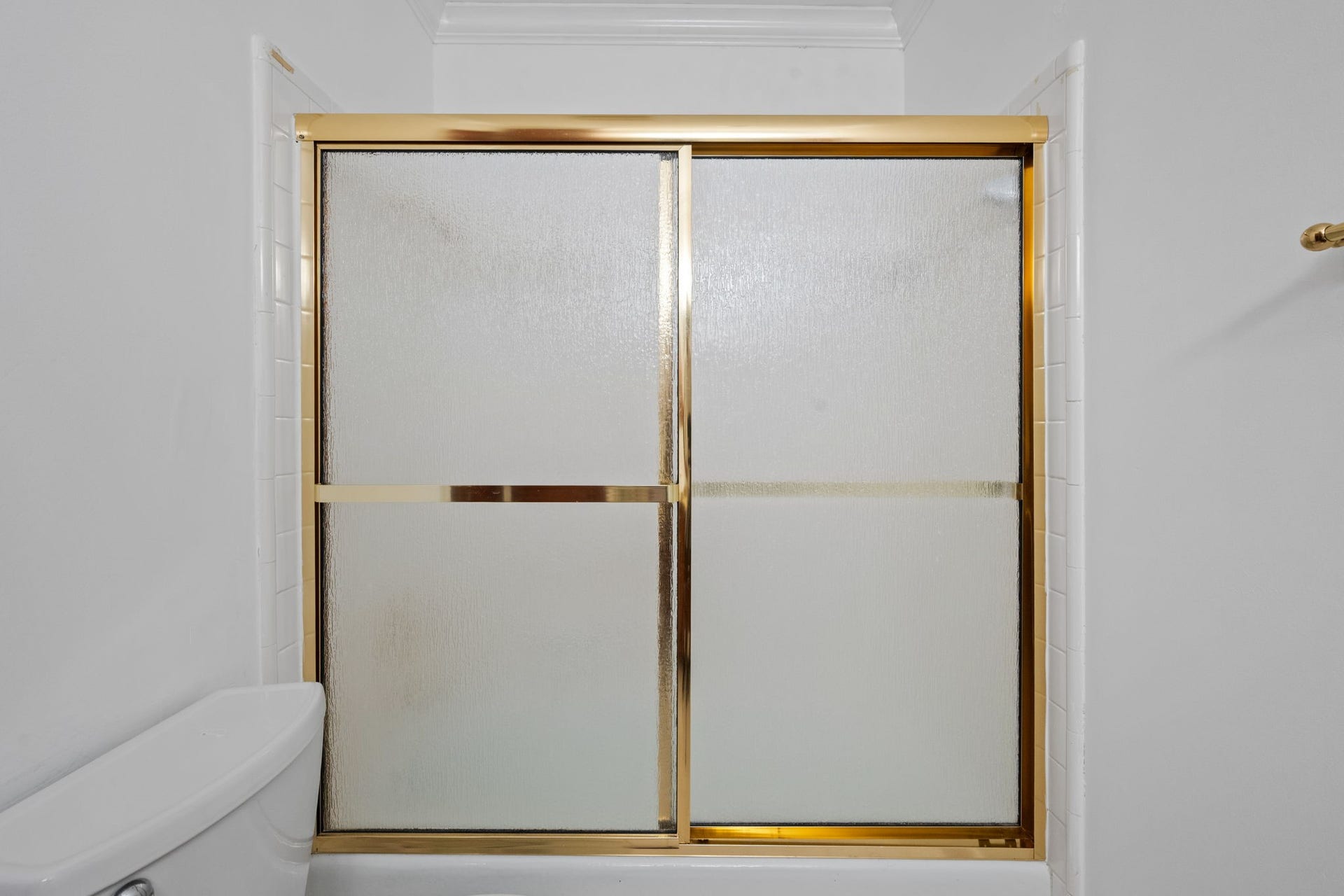5819 Valley Forge Drive, #91, Houston, TX 77057 Elegant bathroom with a frosted glass shower door framed in gold, offering a touch of luxury and privacy.