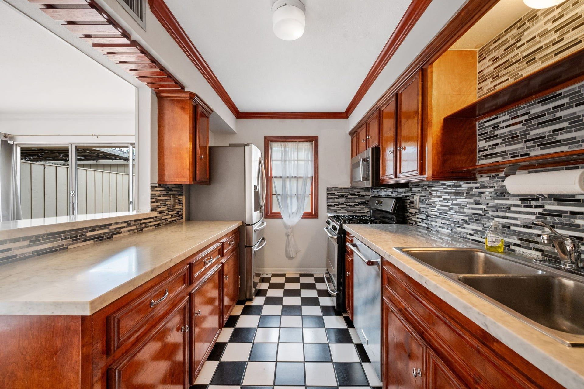 5819 Valley Forge Drive, #91, Houston, TX 77057 Charming kitchen with rich wooden cabinetry and sleek modern backsplash, complemented by a classic black-and-white checkered floor.