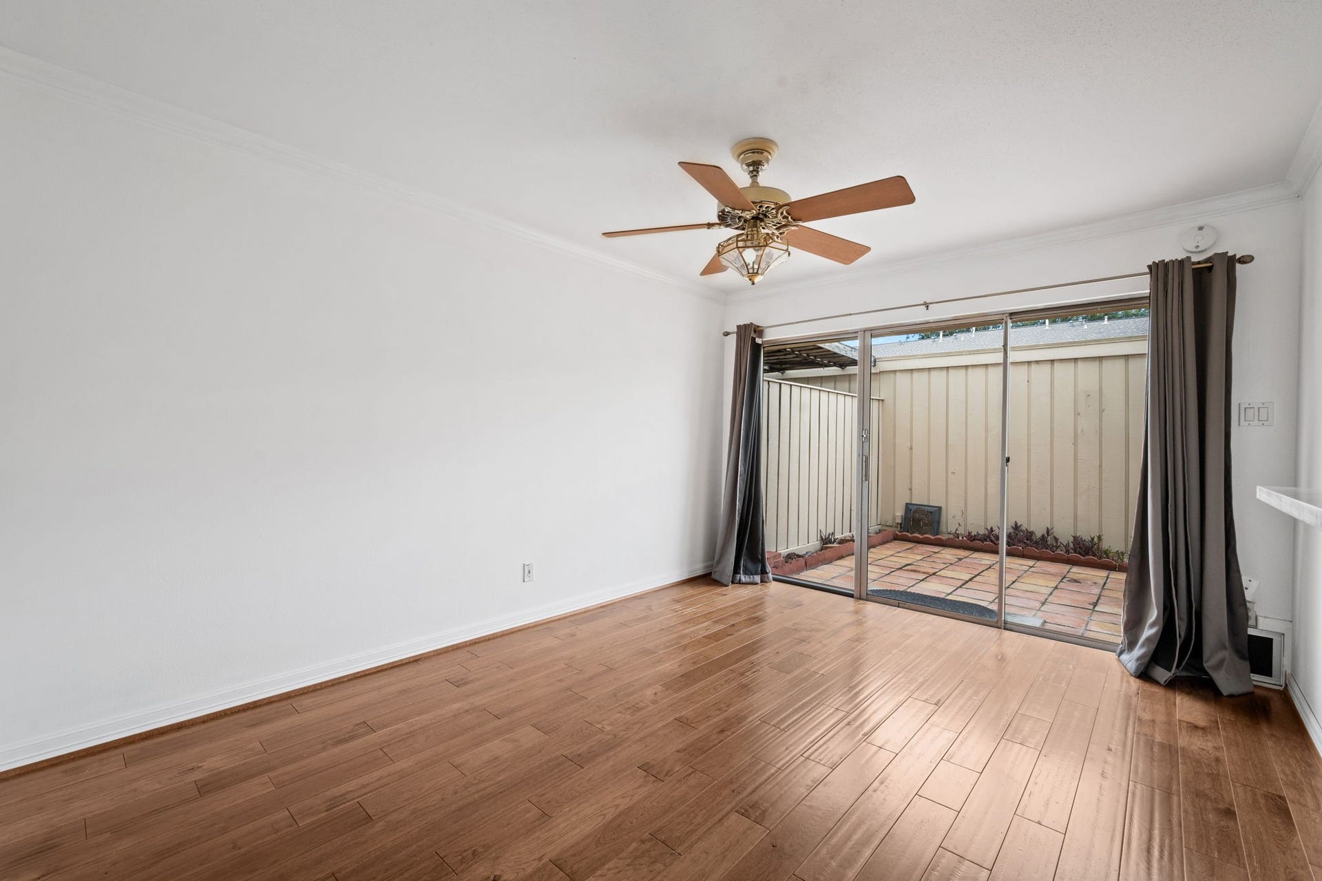 5819 Valley Forge Drive, #91, Houston, TX 77057 Bright and inviting room featuring elegant hardwood floors, a stylish ceiling fan, and sliding glass doors leading to a charming patio.