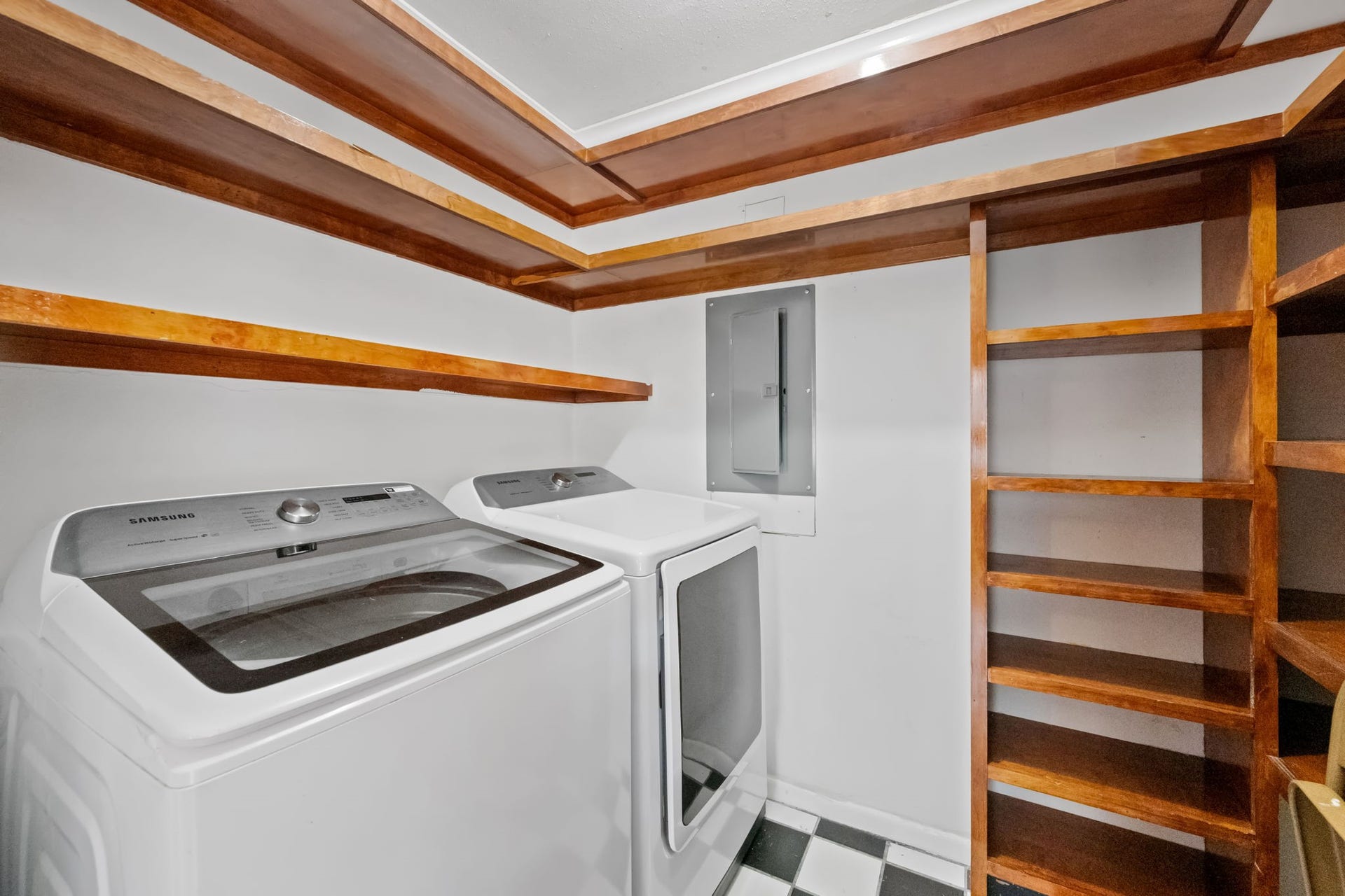 5819 Valley Forge Drive, #91, Houston, TX 77057 Spacious laundry room featuring modern appliances, ample wooden shelving, and a stylish checkerboard floor.