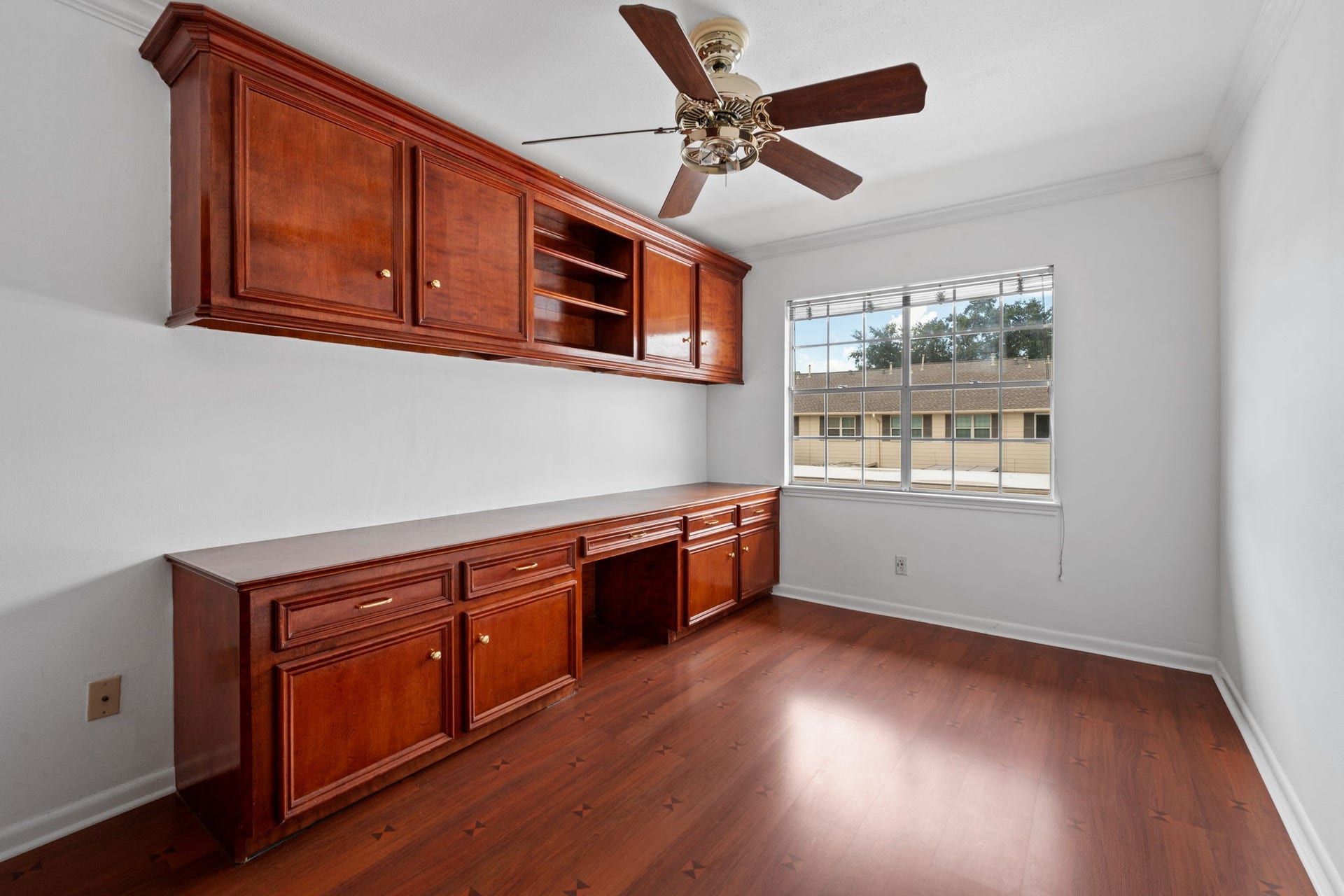 5819 Valley Forge Drive, #91, Houston, TX 77057 Spacious room featuring elegant wood cabinetry and a ceiling fan, complemented by natural light from a large window. Perfect for a home office or study.