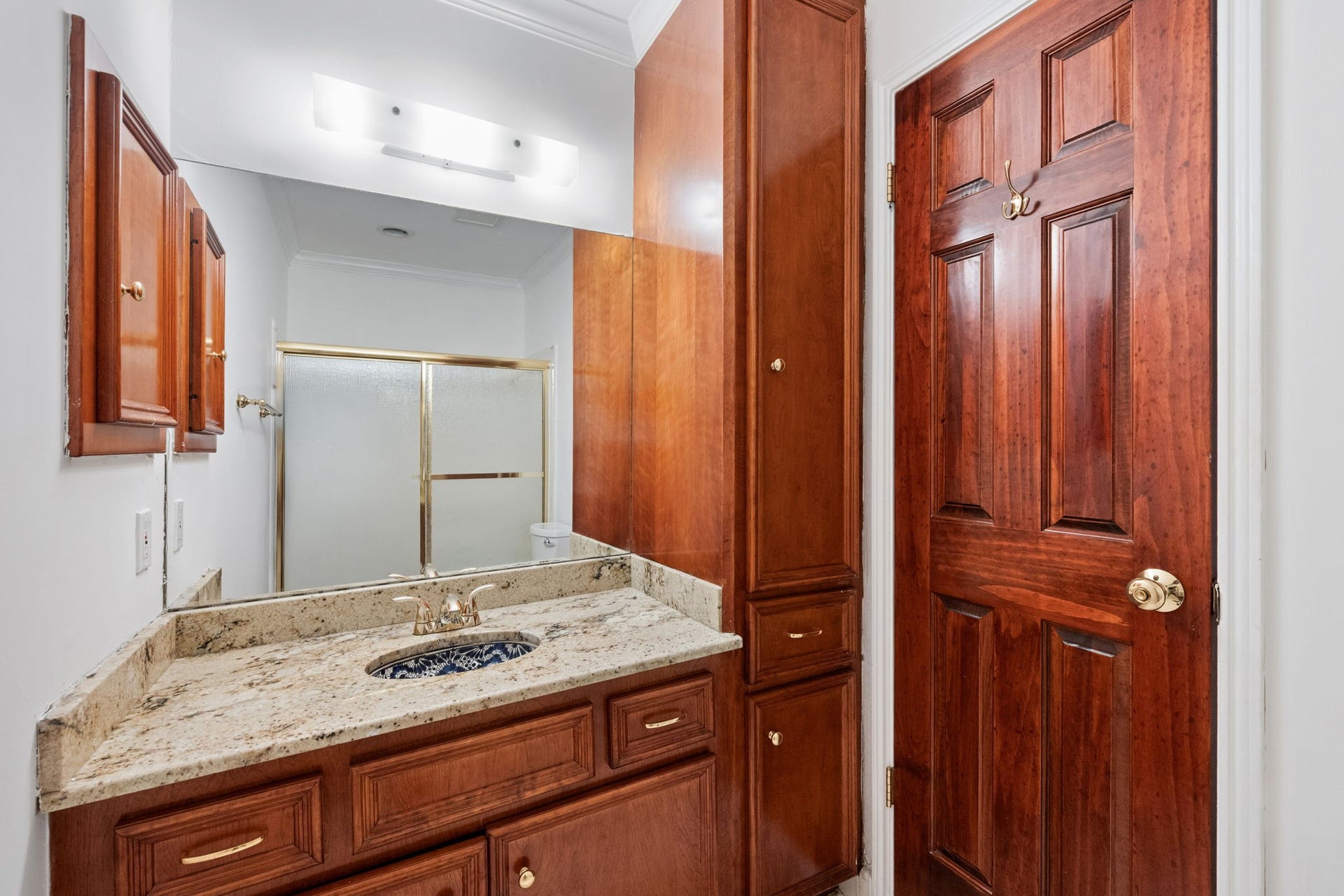 5819 Valley Forge Drive, #91, Houston, TX 77057 Elegant bathroom features rich wood cabinetry, a sleek granite countertop, and a stylish glass-enclosed shower.