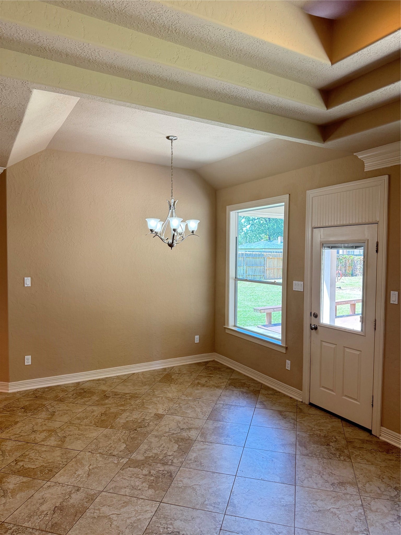 19841 S Plantation Estates Drive, Porter, TX 77365 Bright breakfast area with elegant tile flooring, a charming chandelier, and abundant natural light from a large window and door leading to the backyard.