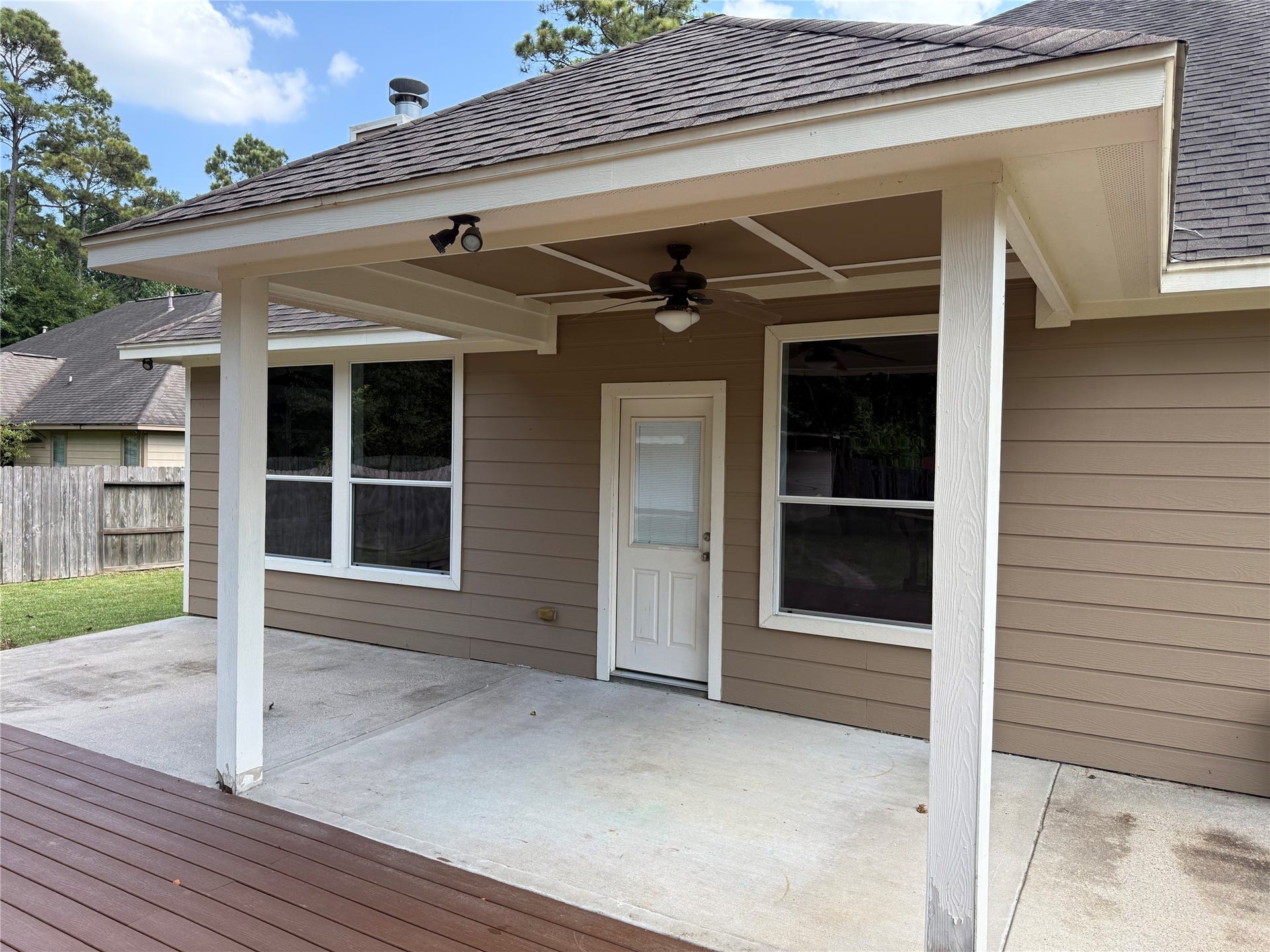 19841 S Plantation Estates Drive, Porter, TX 77365 Charming covered patio with ceiling fan, perfect for outdoor relaxation, overlooking a spacious backyard with a privacy fence.