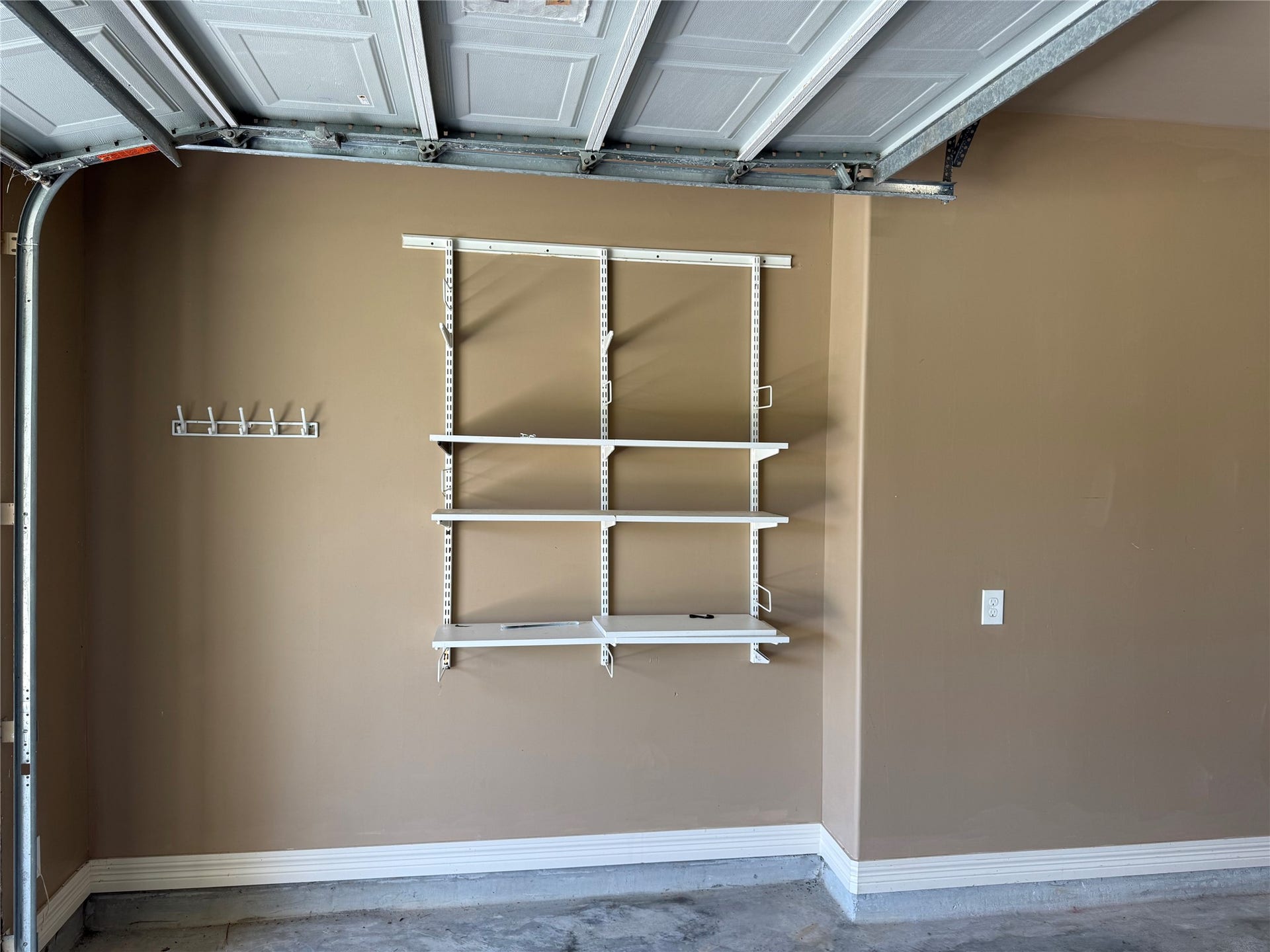 19841 S Plantation Estates Drive, Porter, TX 77365 Spacious garage featuring sturdy wall-mounted shelving and hooks, perfect for organized storage solutions.