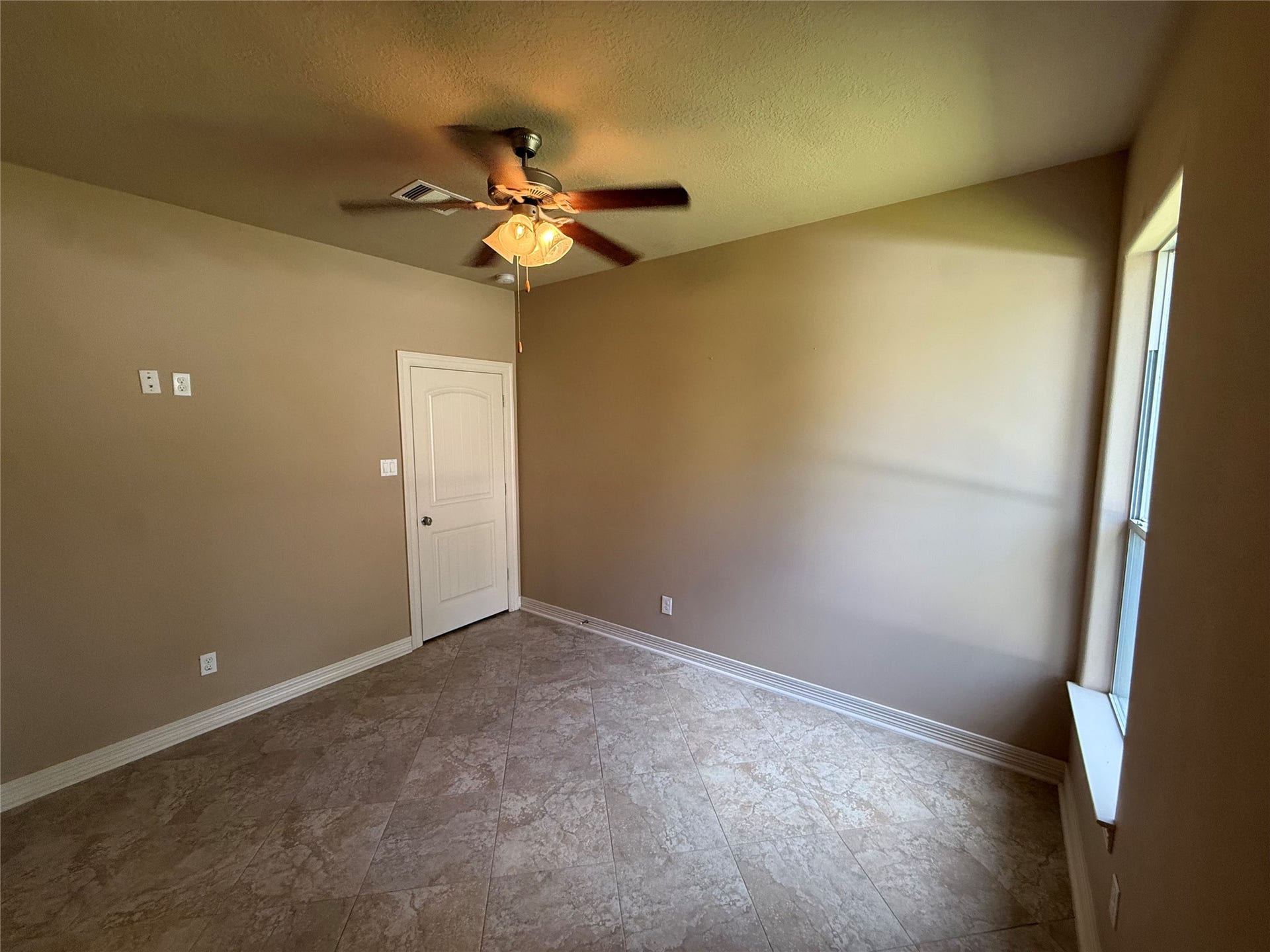19841 S Plantation Estates Drive, Porter, TX 77365 Cozy bedroom with neutral tones, featuring a ceiling fan and natural light from a generous window, complemented by tiled flooring for easy maintenance.