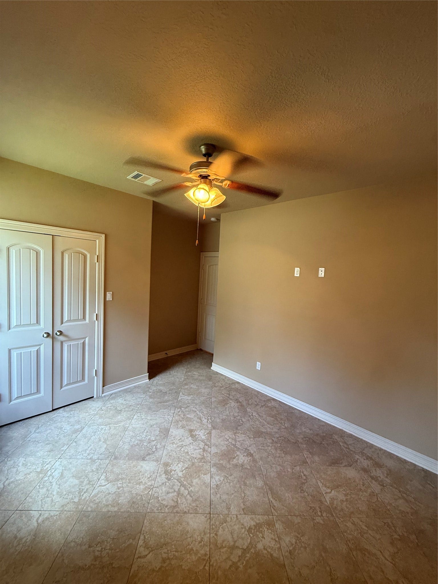 19841 S Plantation Estates Drive, Porter, TX 77365 Spacious room with elegant tiled flooring, a ceiling fan for comfort, and double doors providing ample storage.