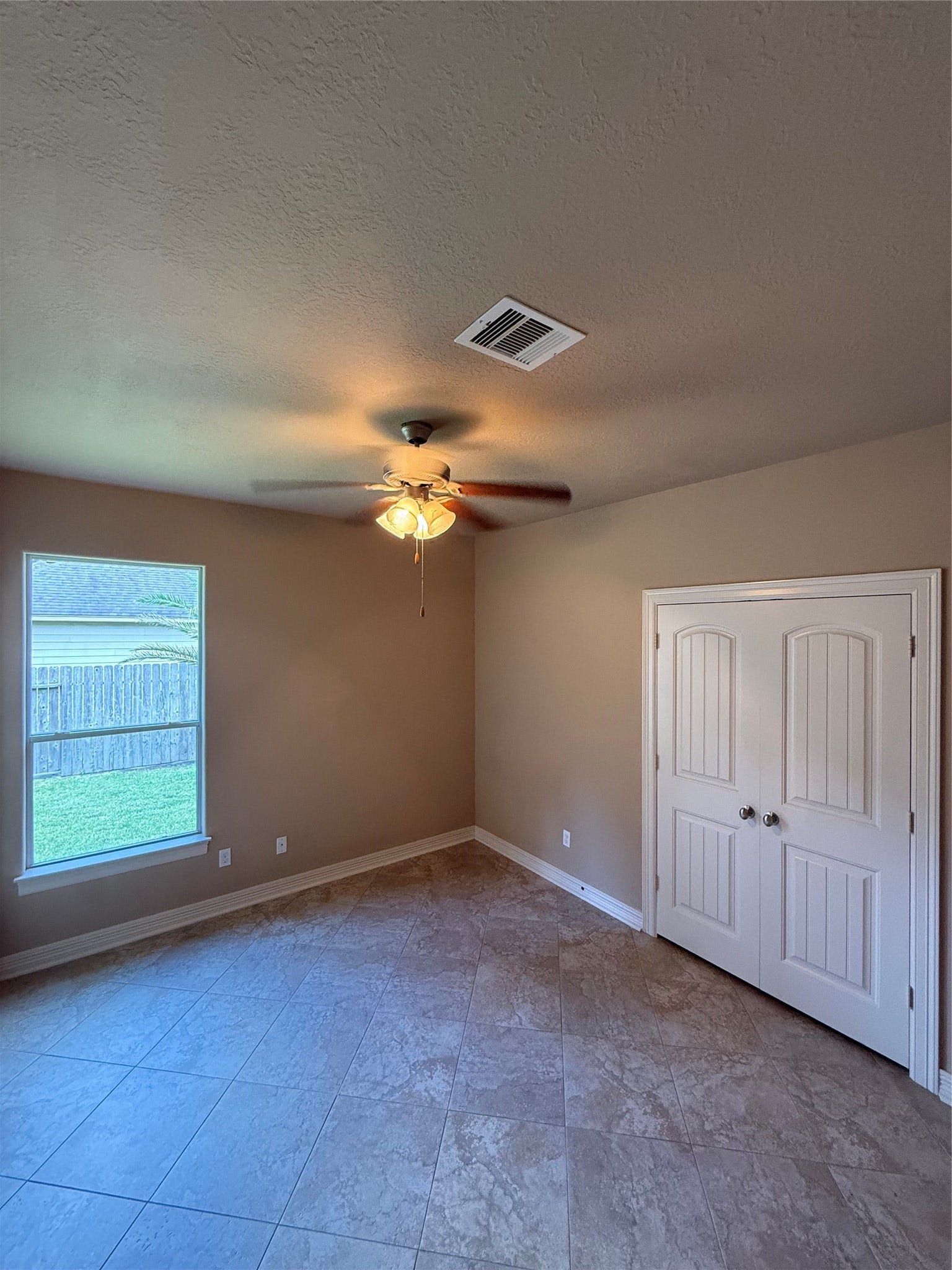 19841 S Plantation Estates Drive, Porter, TX 77365 Bright room with neutral tones, featuring a ceiling fan, tiled flooring, and a double-door closet, offering a cozy and functional space.