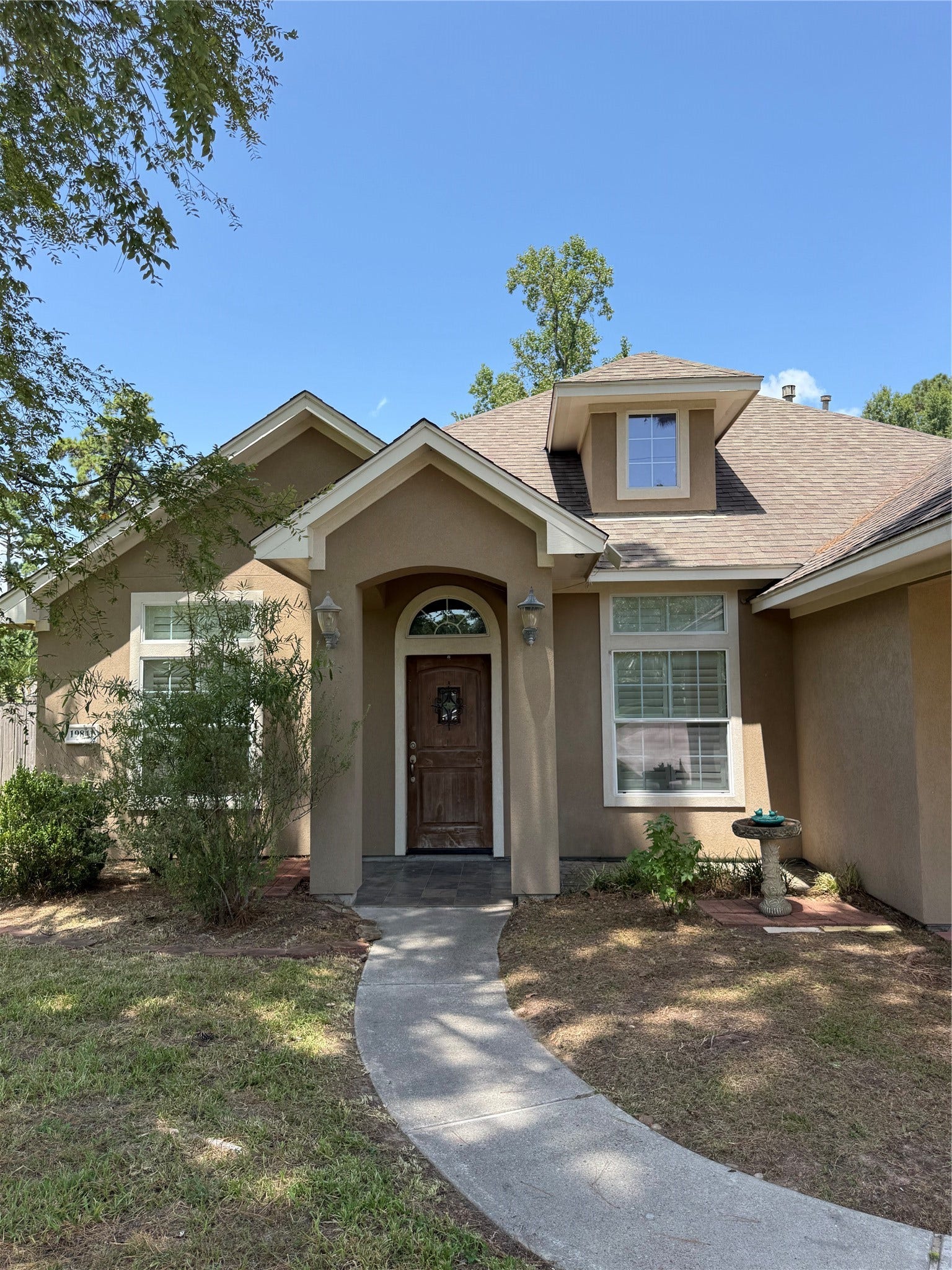 19841 S Plantation Estates Drive, Porter, TX 77365 Charming home with a welcoming front entrance, featuring a classic wooden door and well-maintained landscaping along a curved walkway.