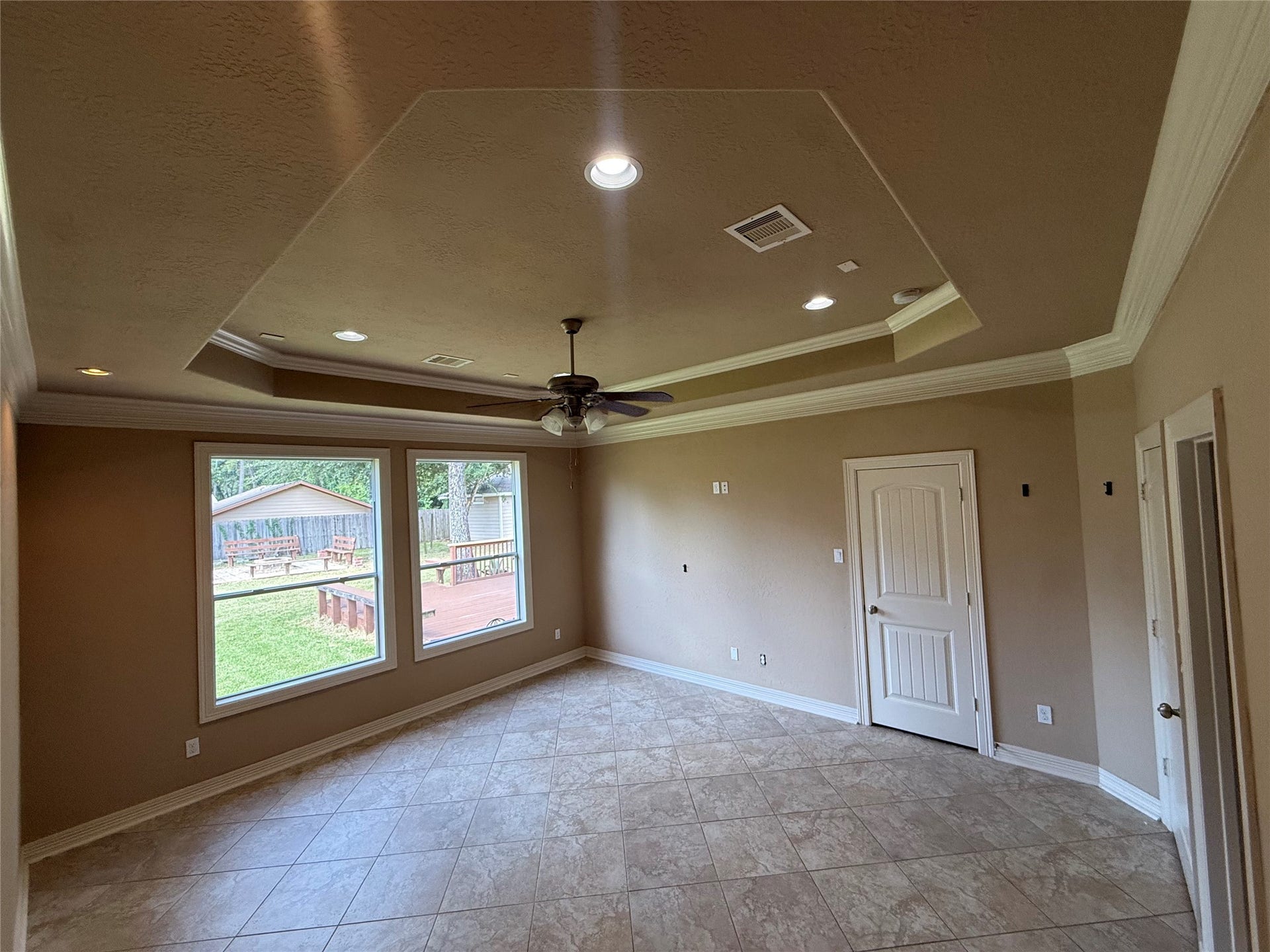 19841 S Plantation Estates Drive, Porter, TX 77365 Spacious Primary bedroom with elegant tray ceiling, & recessed lighting. Large windows offer abundant natural light and views of the backyard.