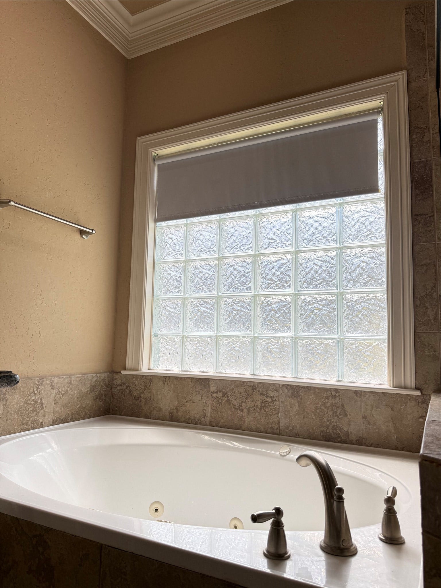 19841 S Plantation Estates Drive, Porter, TX 77365 Luxurious bathroom featuring a large soaking tub with elegant fixtures, set against a backdrop of textured glass windows for privacy and natural light.