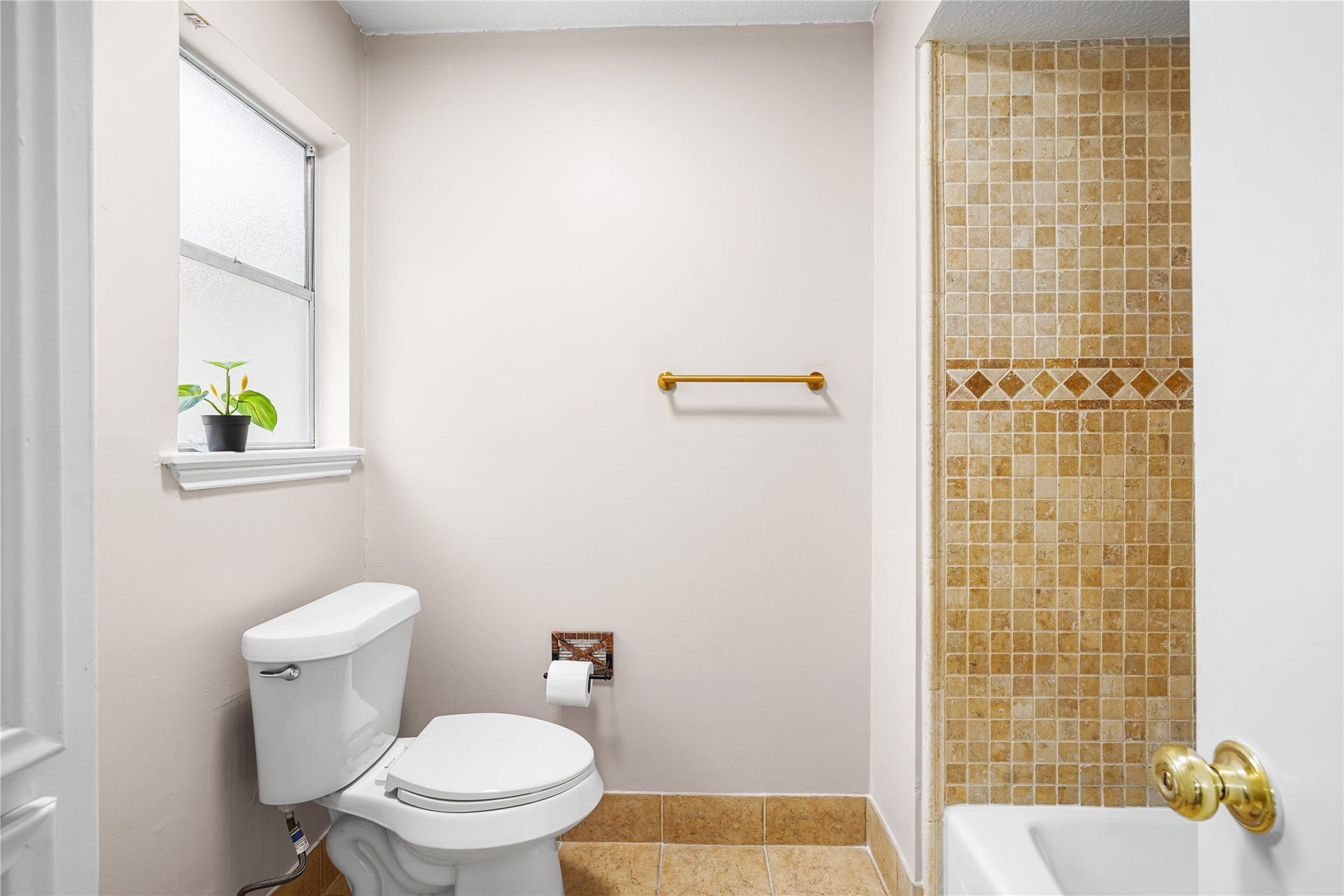 Bright, inviting bathroom with elegant tile work, a modern toilet, and a window providing natural light.
