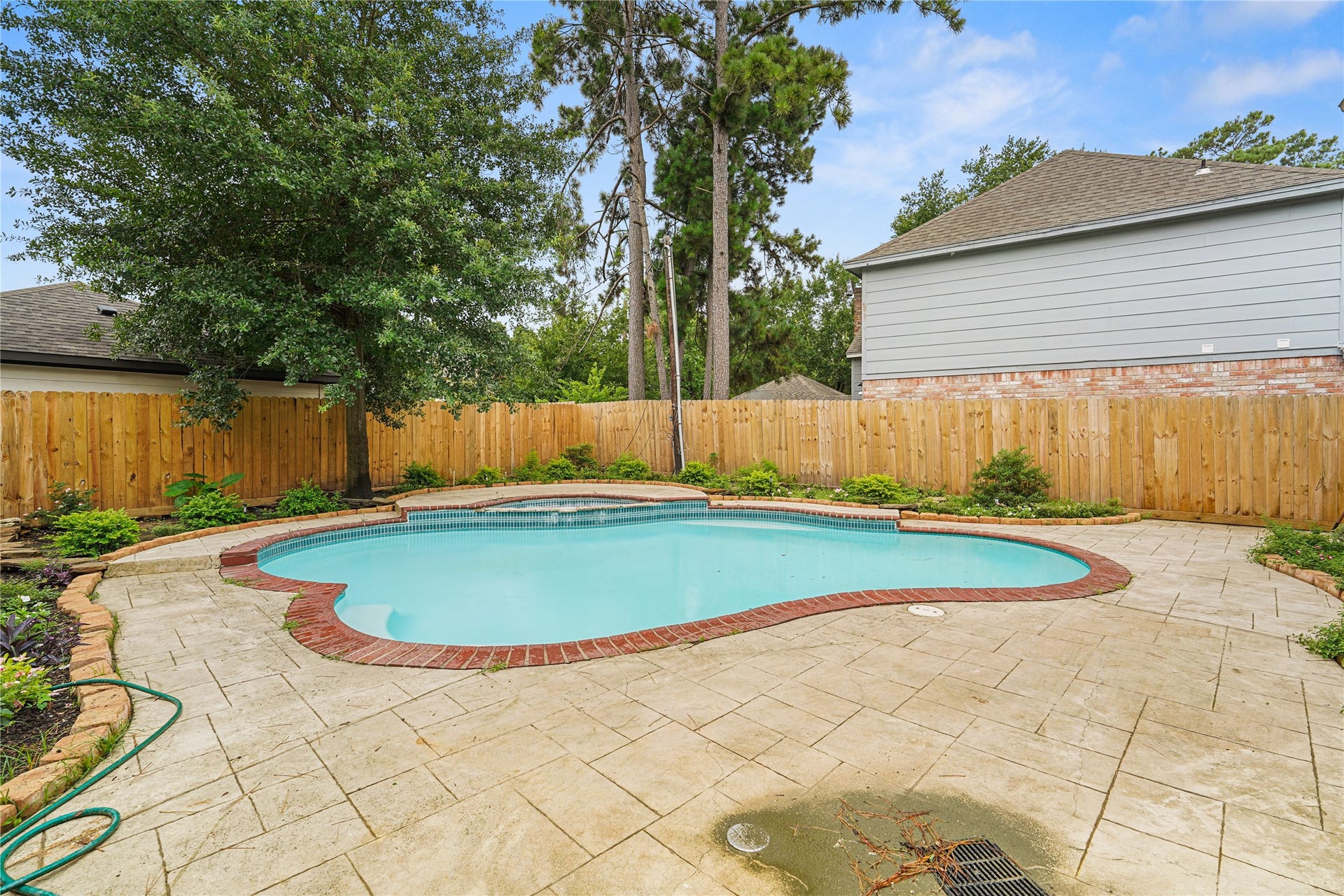 Discover a charming backyard retreat featuring a pool, surrounded by a spacious stone patio, lush greenery, and a privacy fenceperfect for relaxation and entertaining.